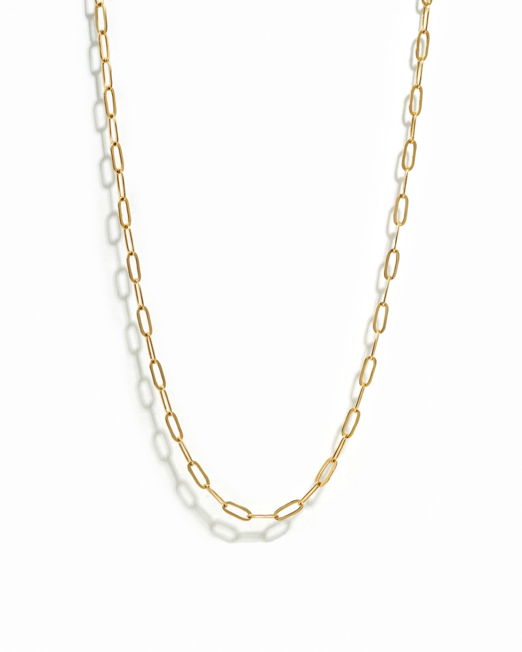 Gold paperclip chain necklace on a white background