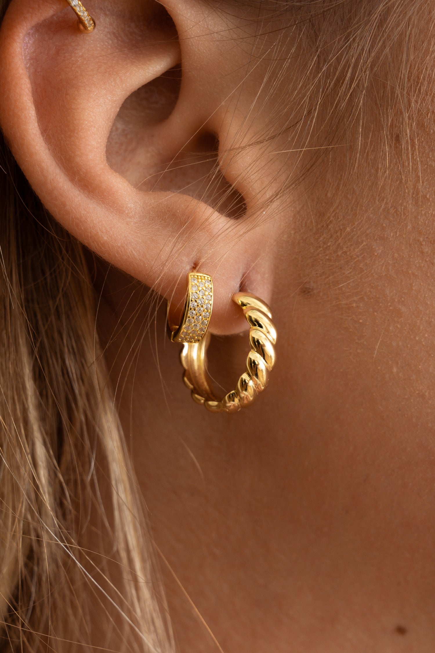 Model wearing gold textured hoops with pave huggies