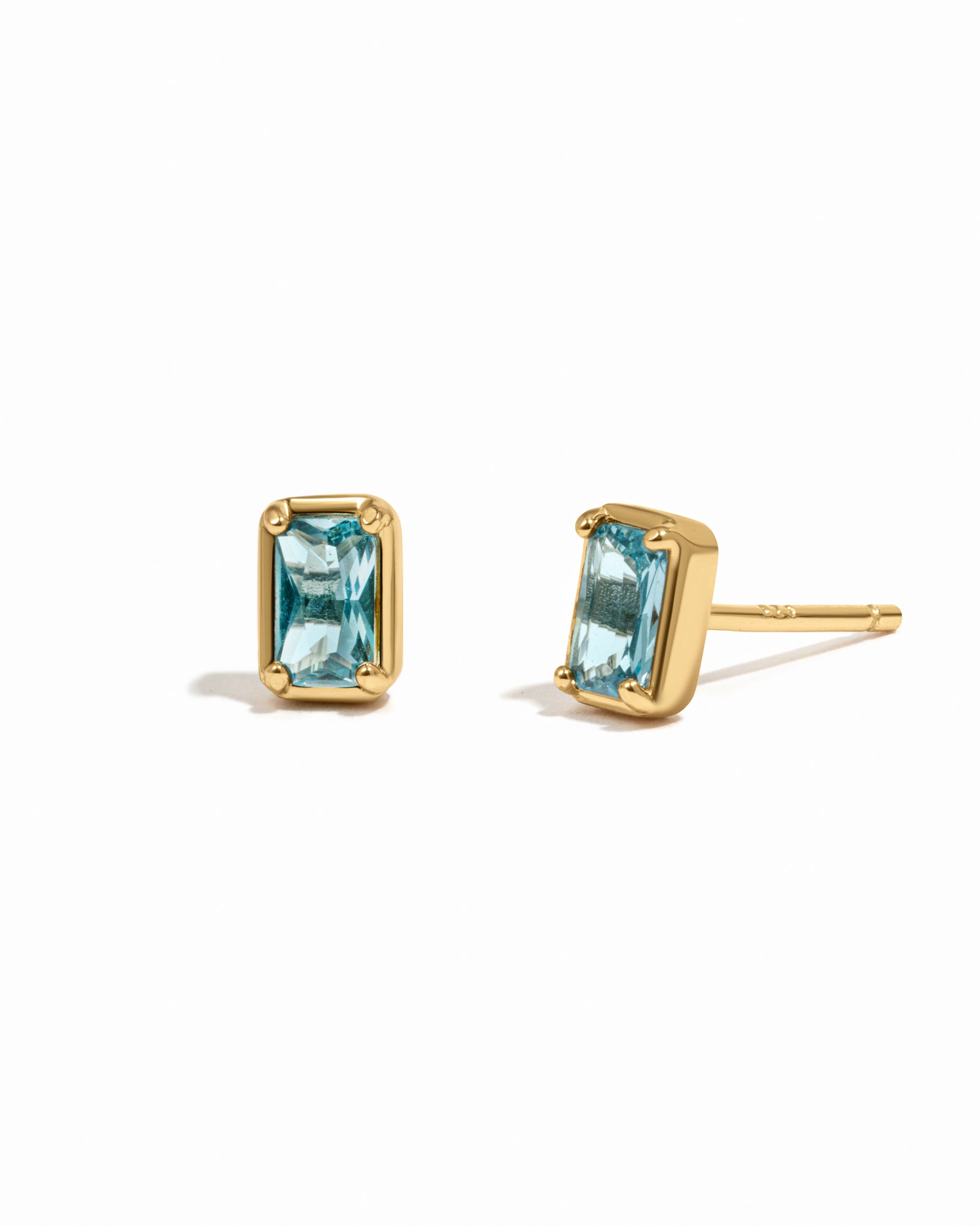 Elegant aquamarine birthstone baguette stud earrings with 14k gold plated sterling silver on white background.