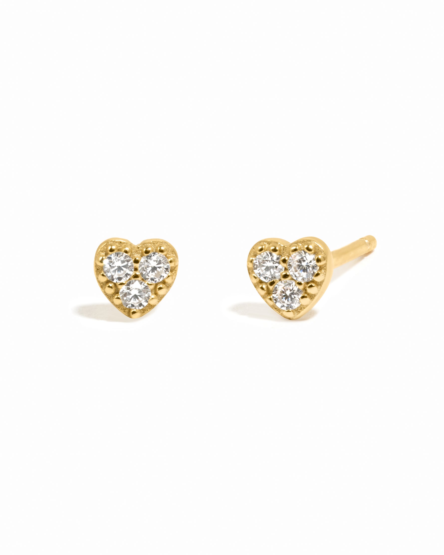 Gold delicate cz studded heart stud earrings on white background.