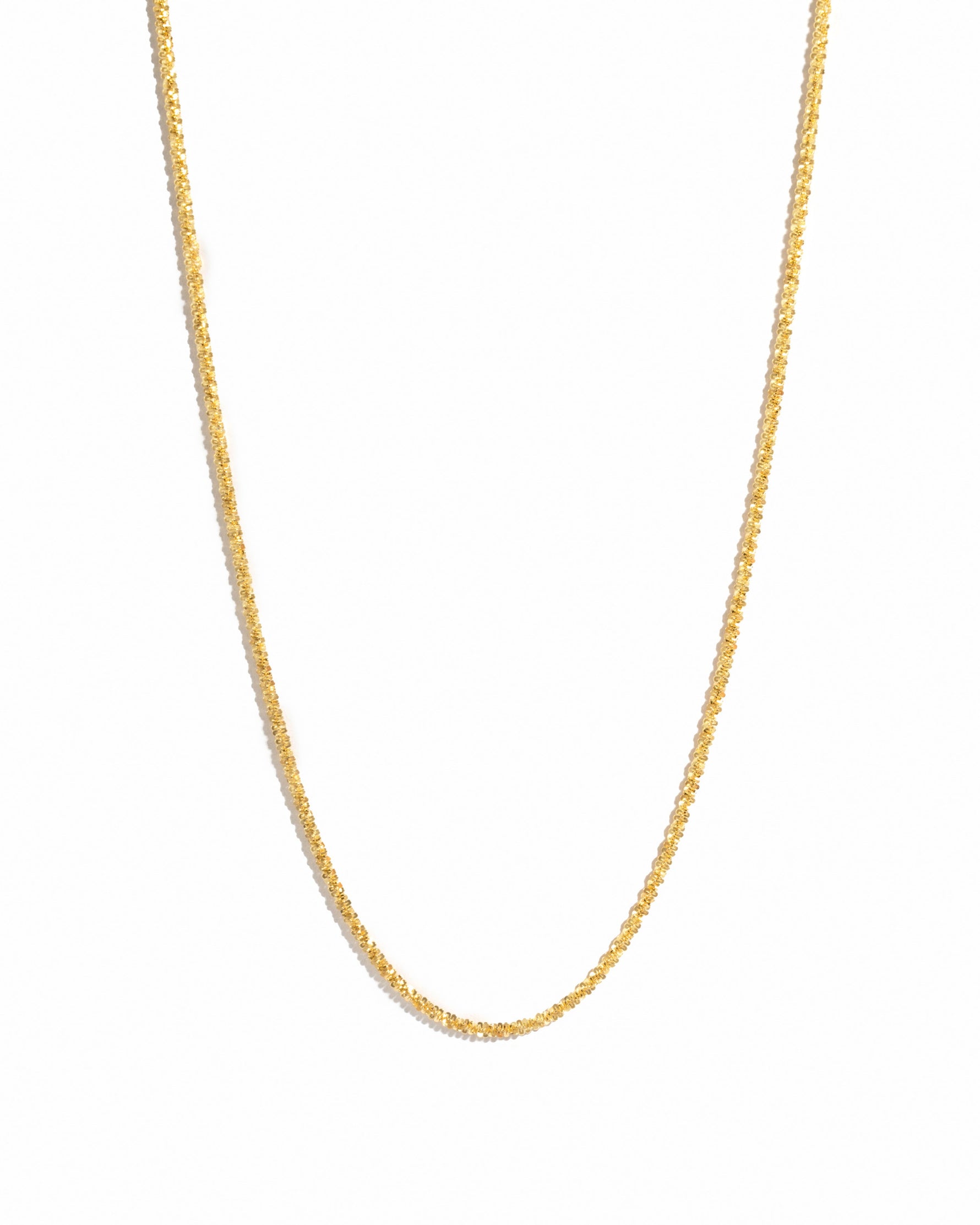 Gold diamond cut chain necklace on white background
