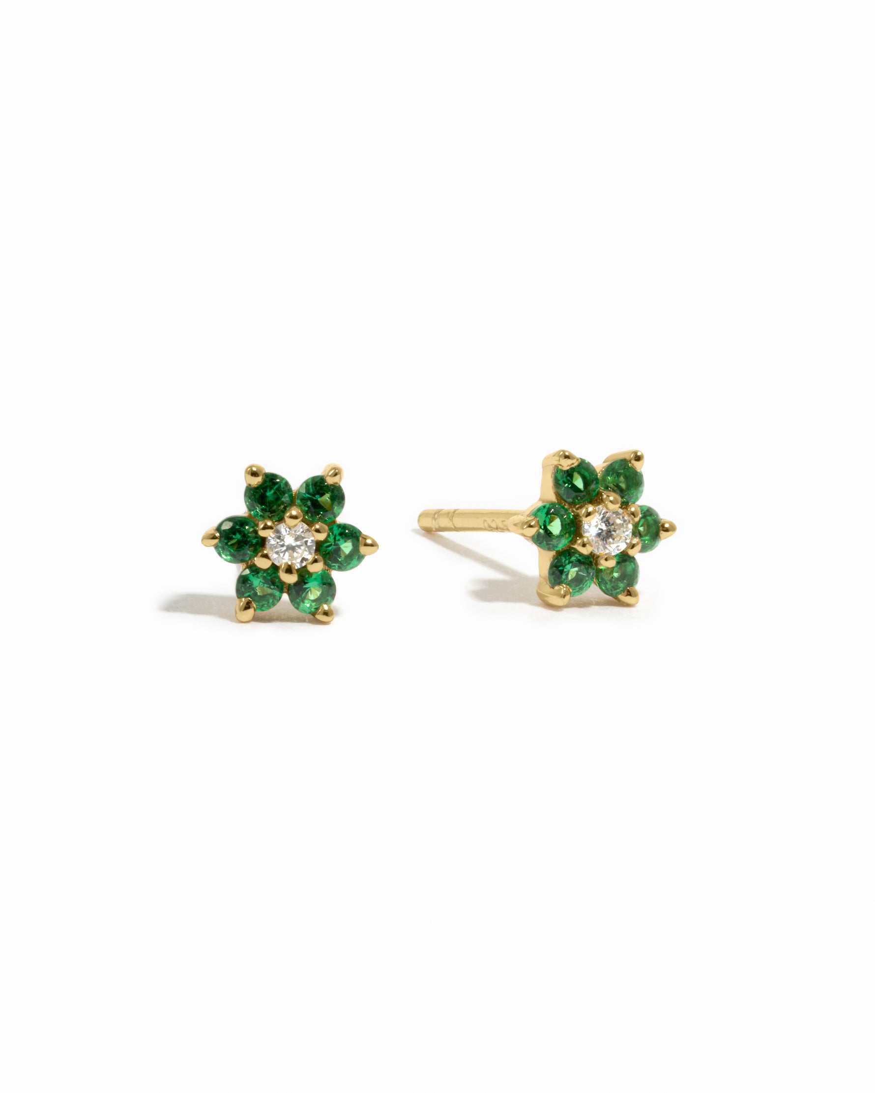 Dainty gold emerald birthstone flower stud earrings with white diamond in the center on white background.