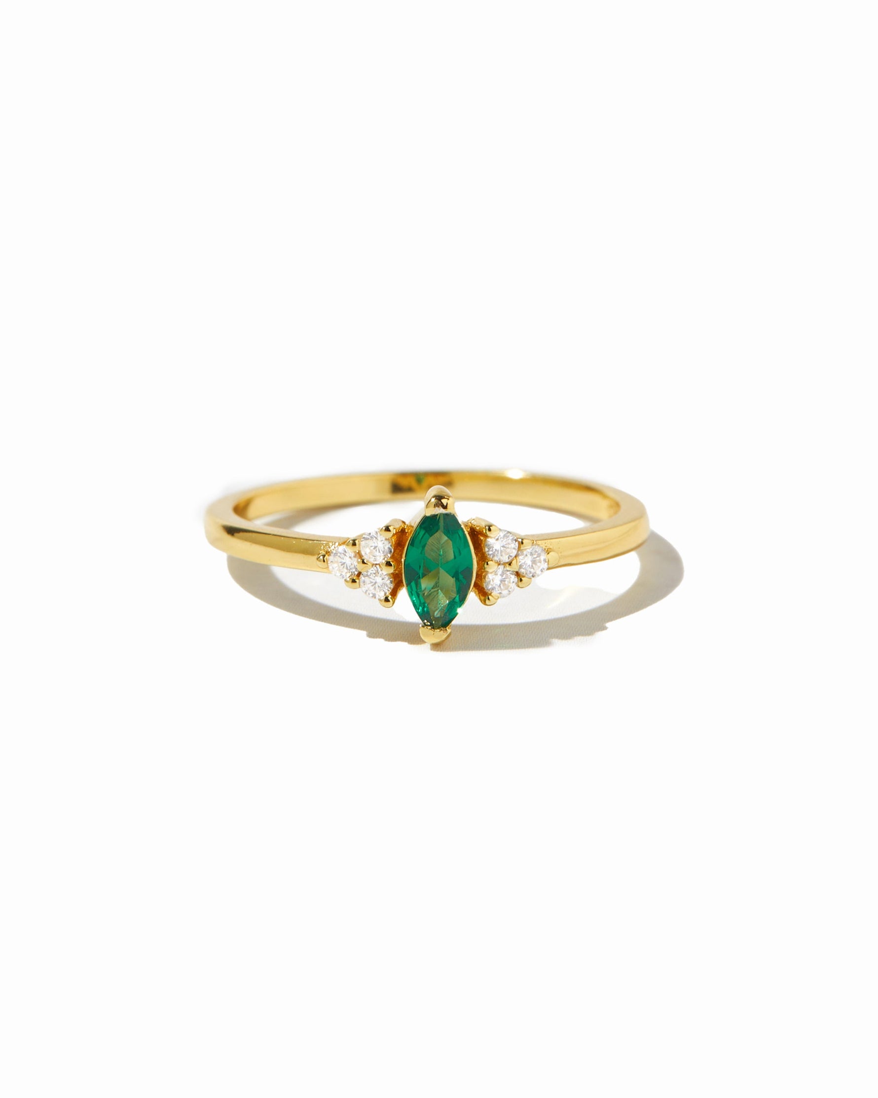 Emerald marquise birthstone ring on white background.