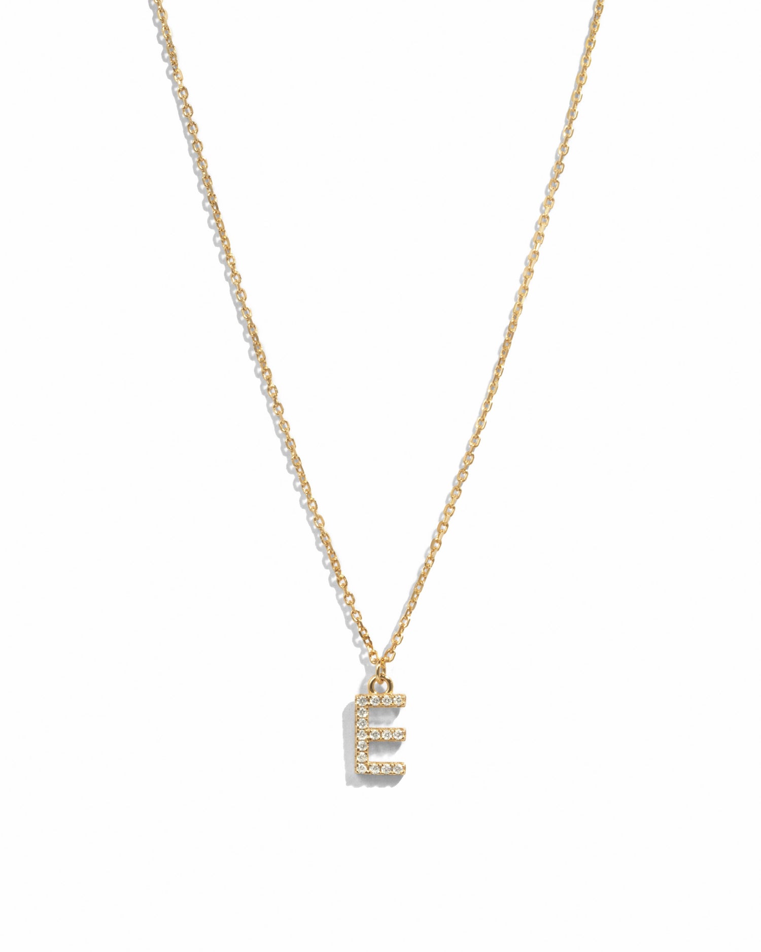 Dainty gold studded initial letter pendant necklace on white background