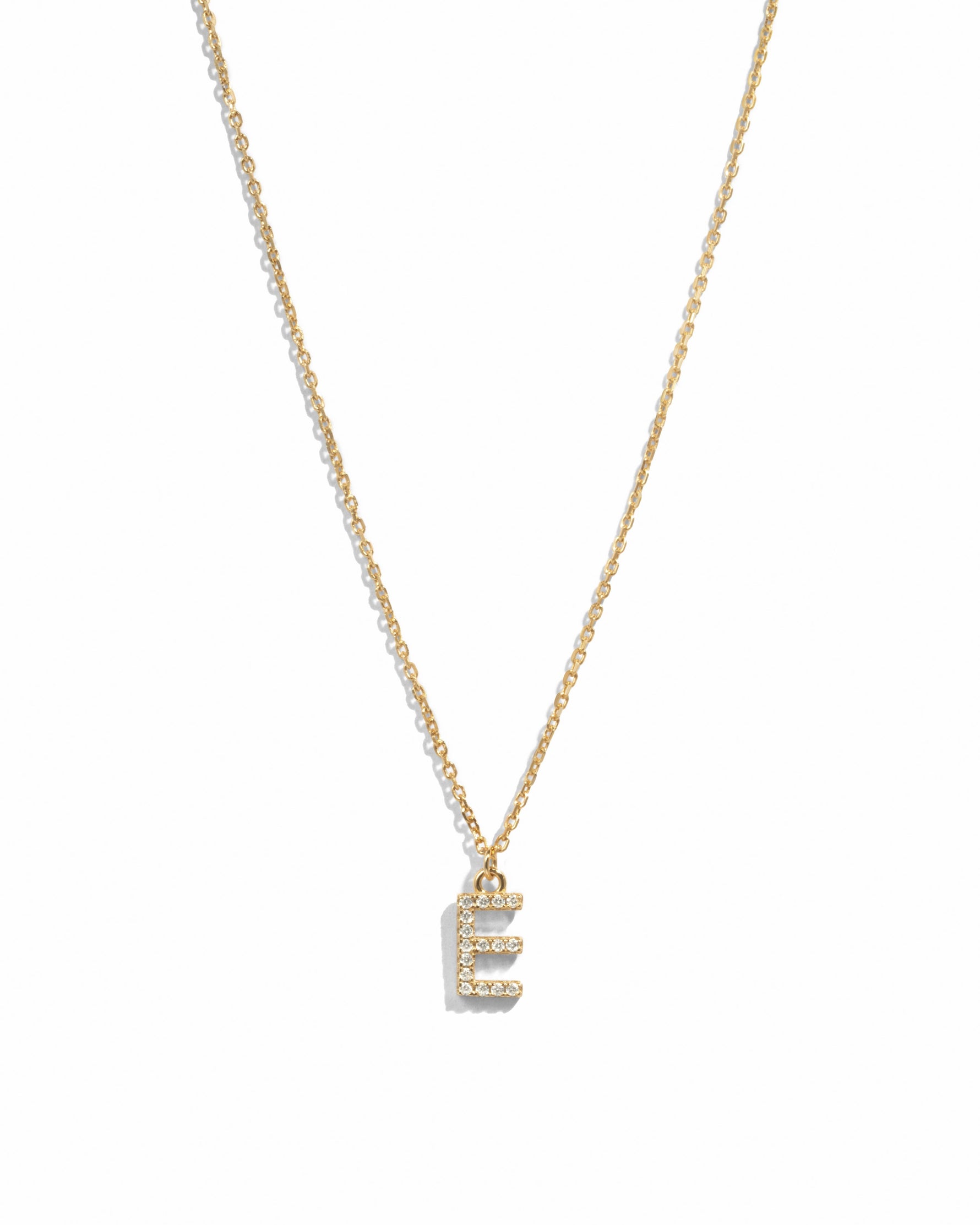 Dainty gold studded initial letter pendant necklace on white background