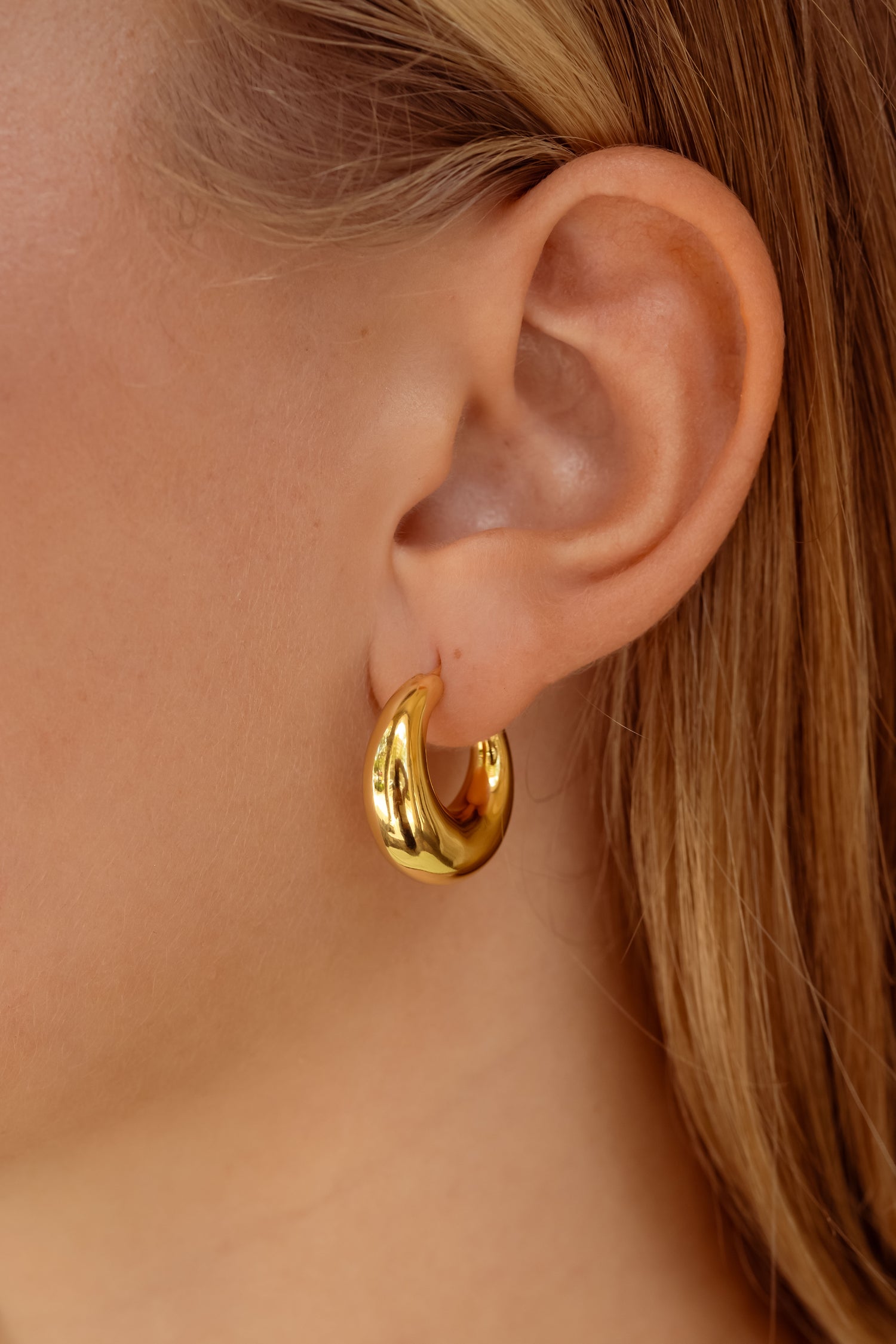 Model wearing honey gold chunky hoop earrings.