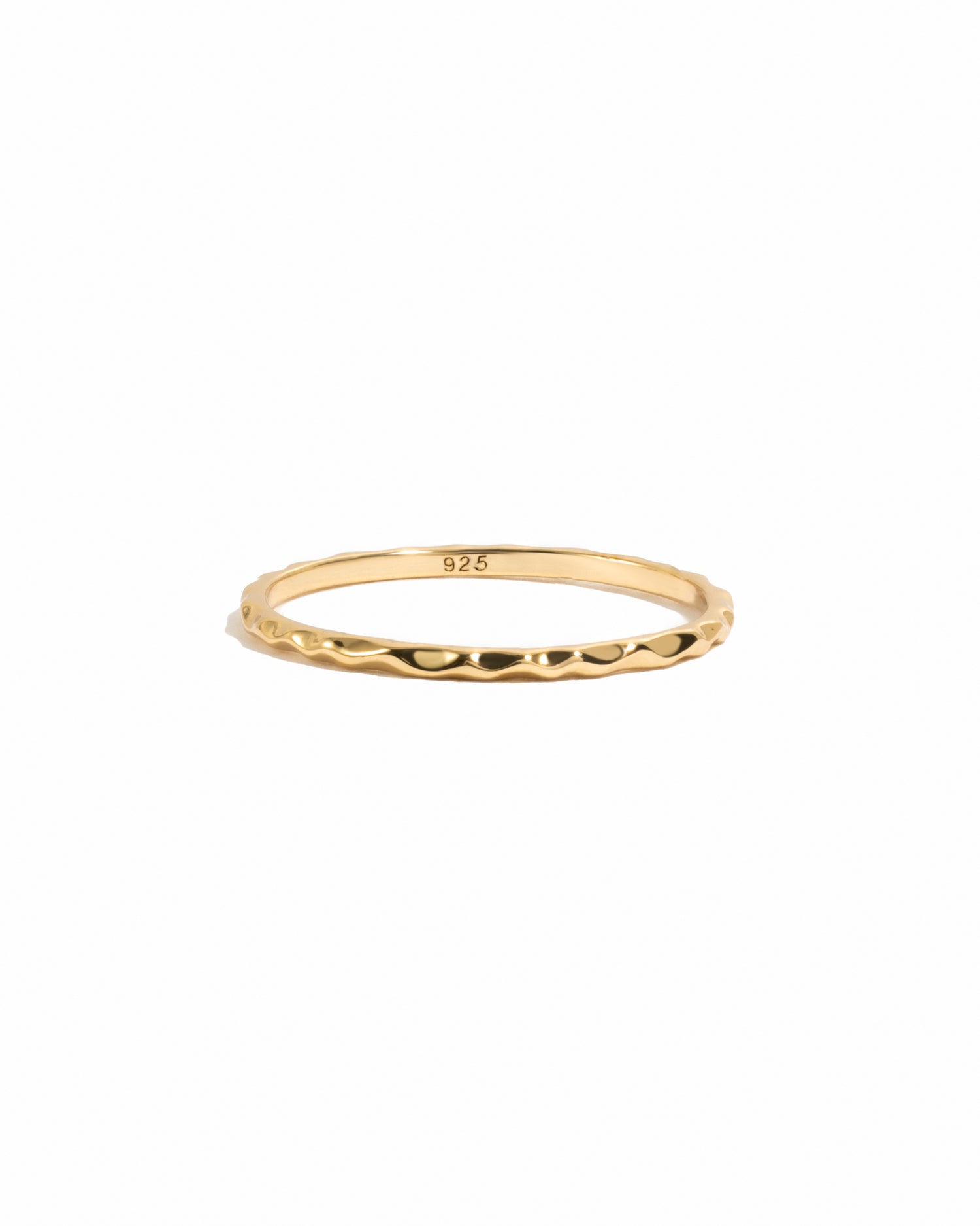 Gold thin plain hammered band on white background.