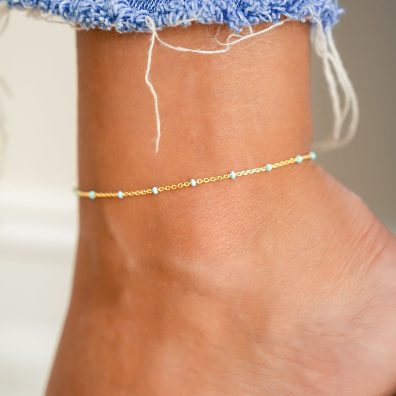 Model wearing beachy gold turquoise beaded ankle bracelet