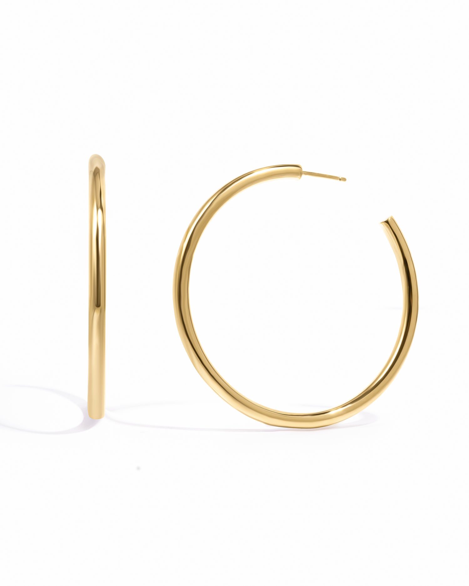 Large gold classic tube hoop earrings on white background. Inspired by Madison Beer's everyday hoop earrings.
