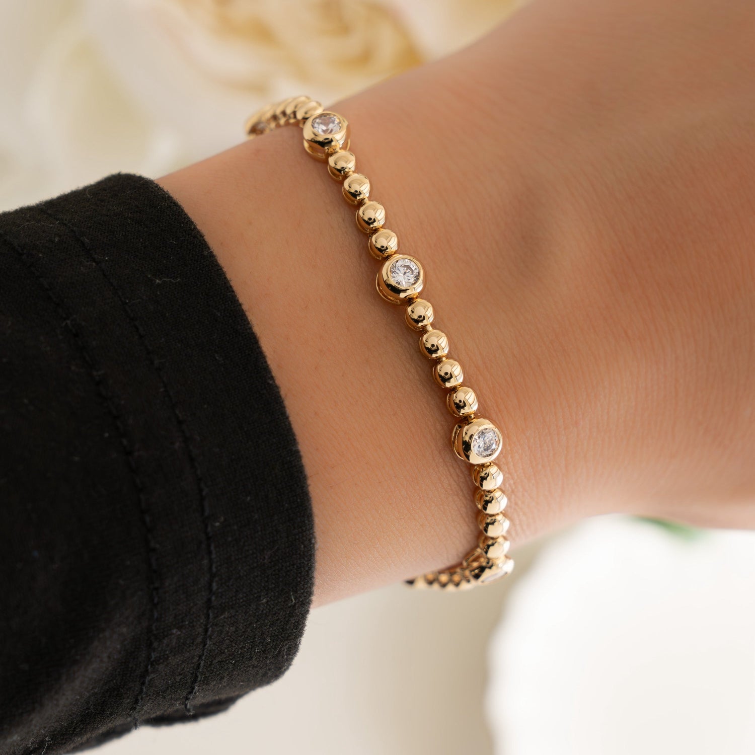 Dainty diamond bracelet in tennis chain, crafted in gold, on a model’s wrist.