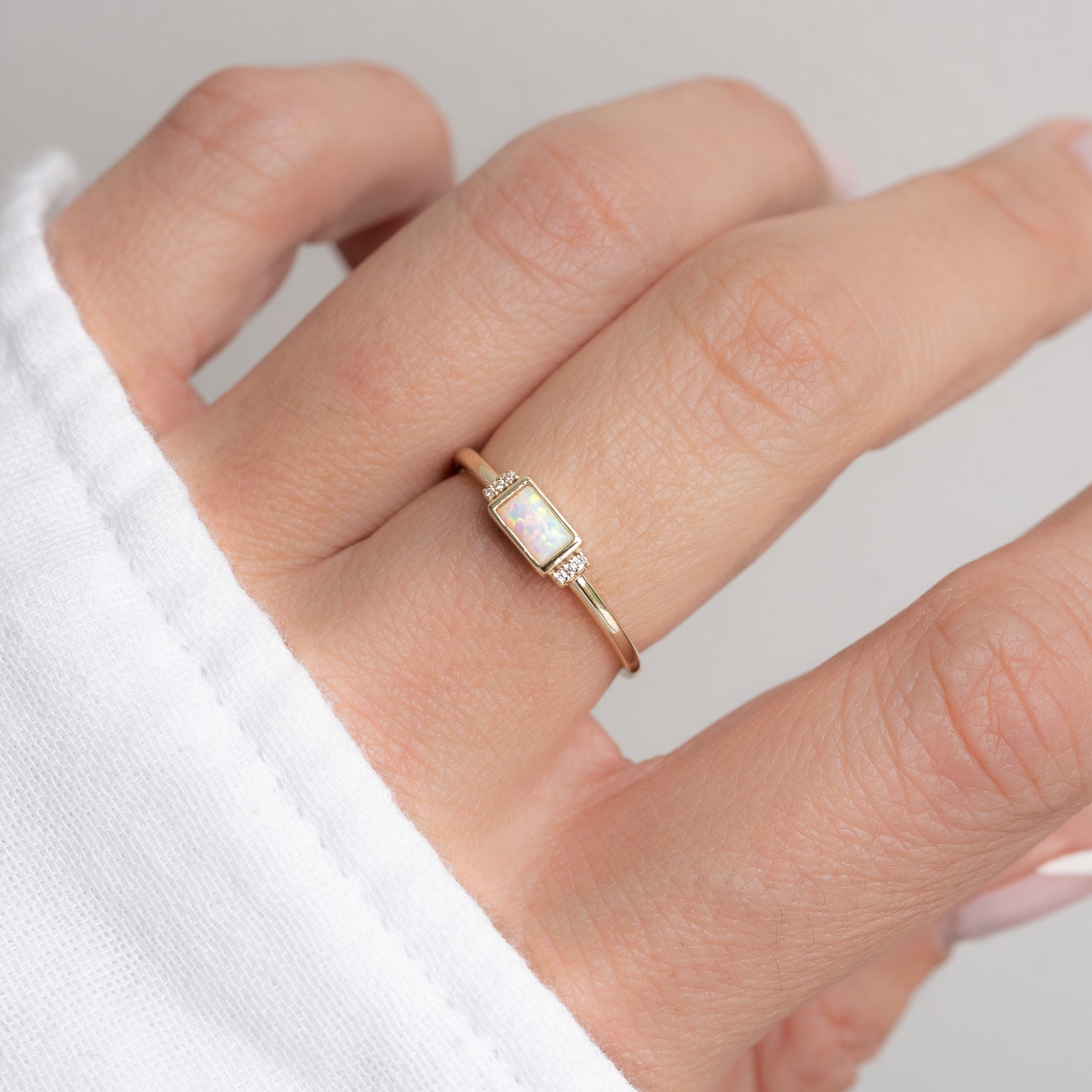 Gold opal baguette ring with side stones on models hand.