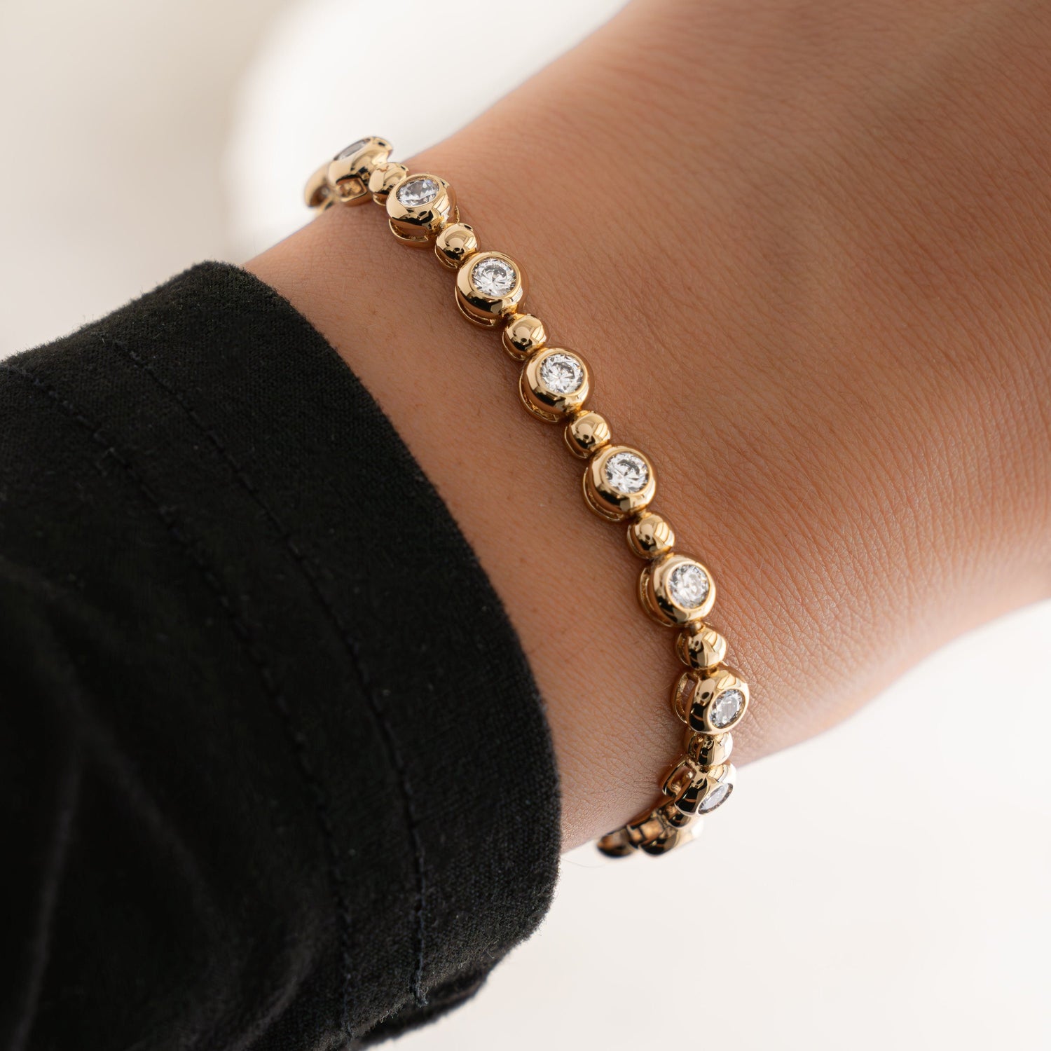 Model wearing stackable diamond bracelets in gold.