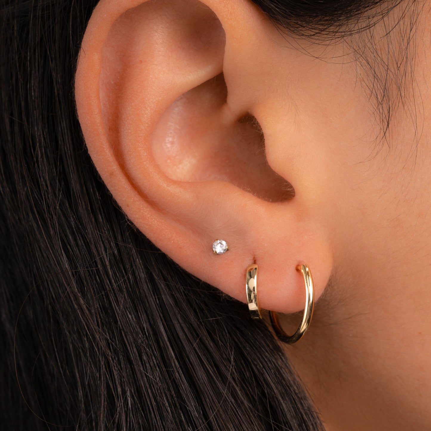 Model wearing gold earring stack featuring 13mm thin hoop earrings