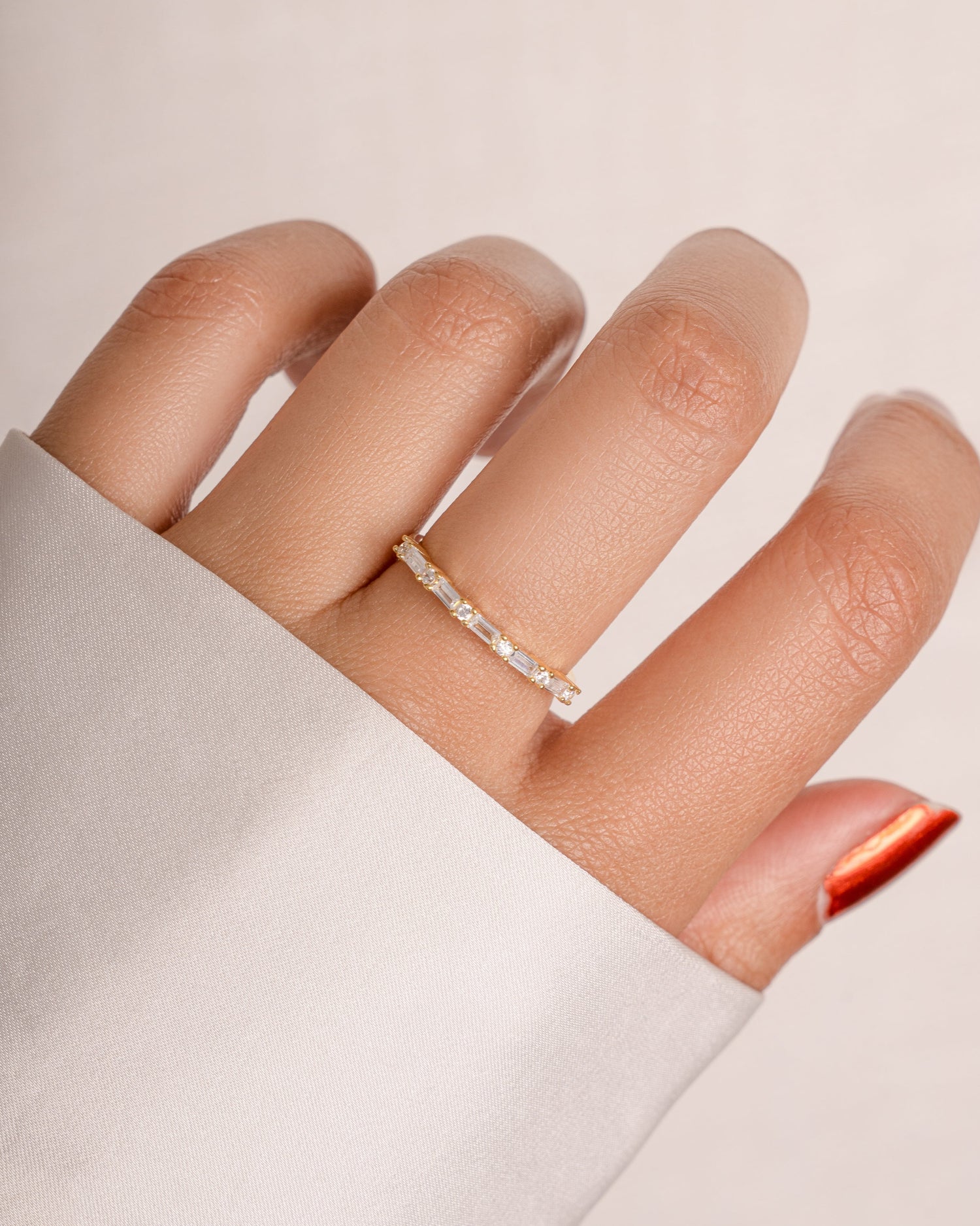 Close-up of a hand wearing a silver ring on a plain background