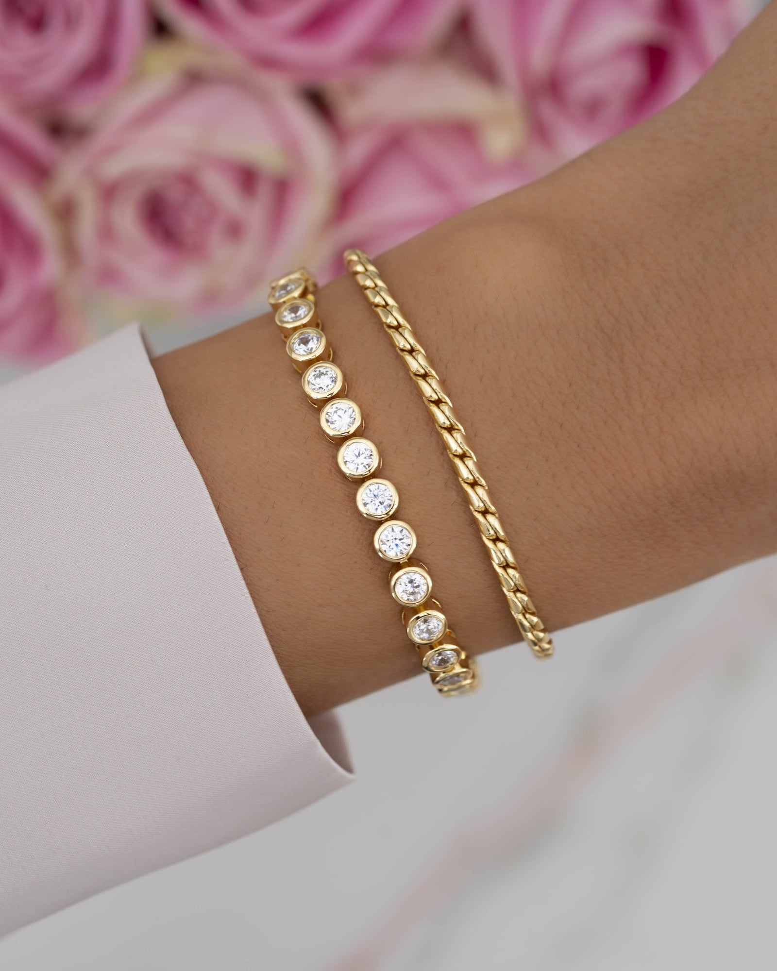 Gold tennis bracelet and dainty chain bracelet on models wrist