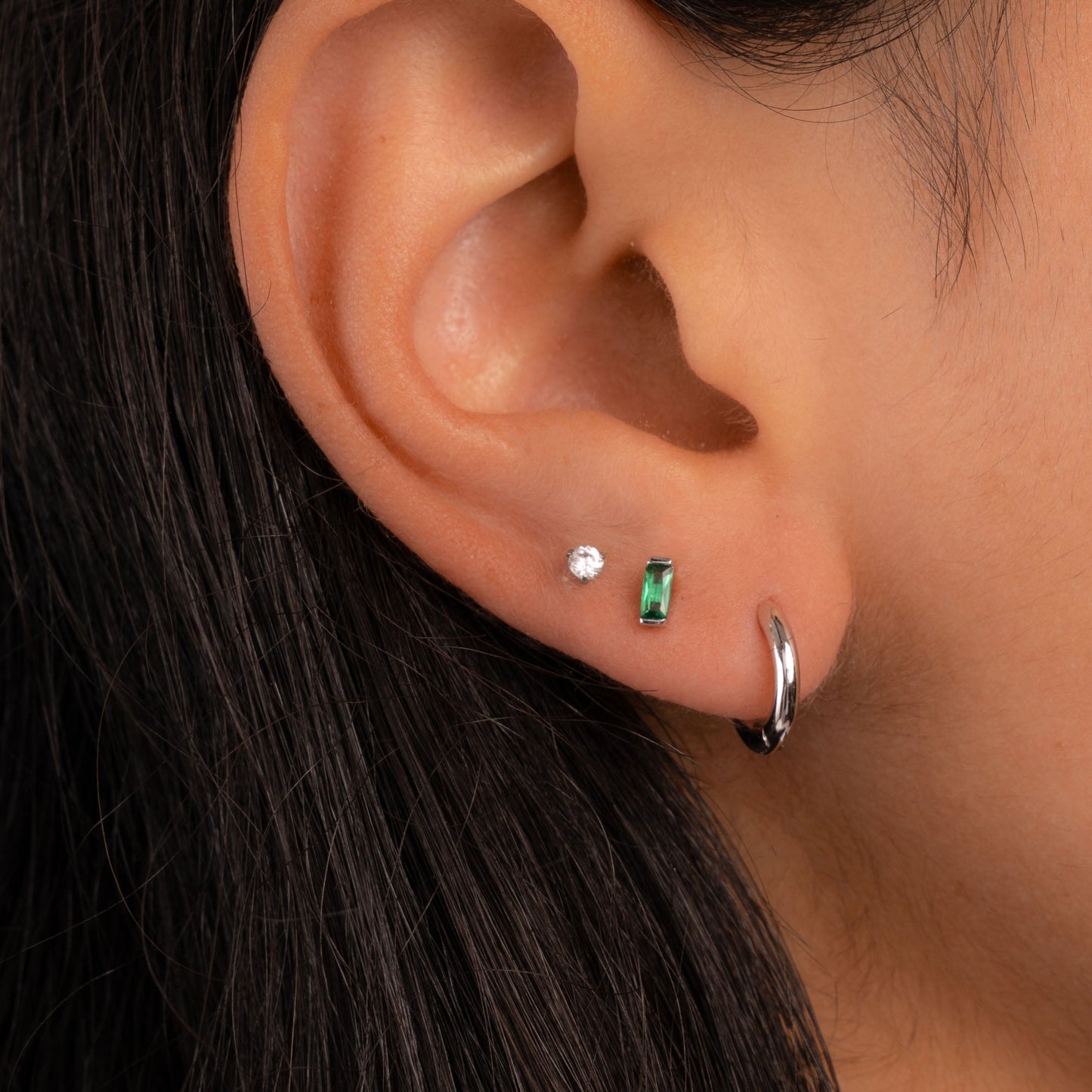 model wearing silver earring stack featuring emerald tiny earrings