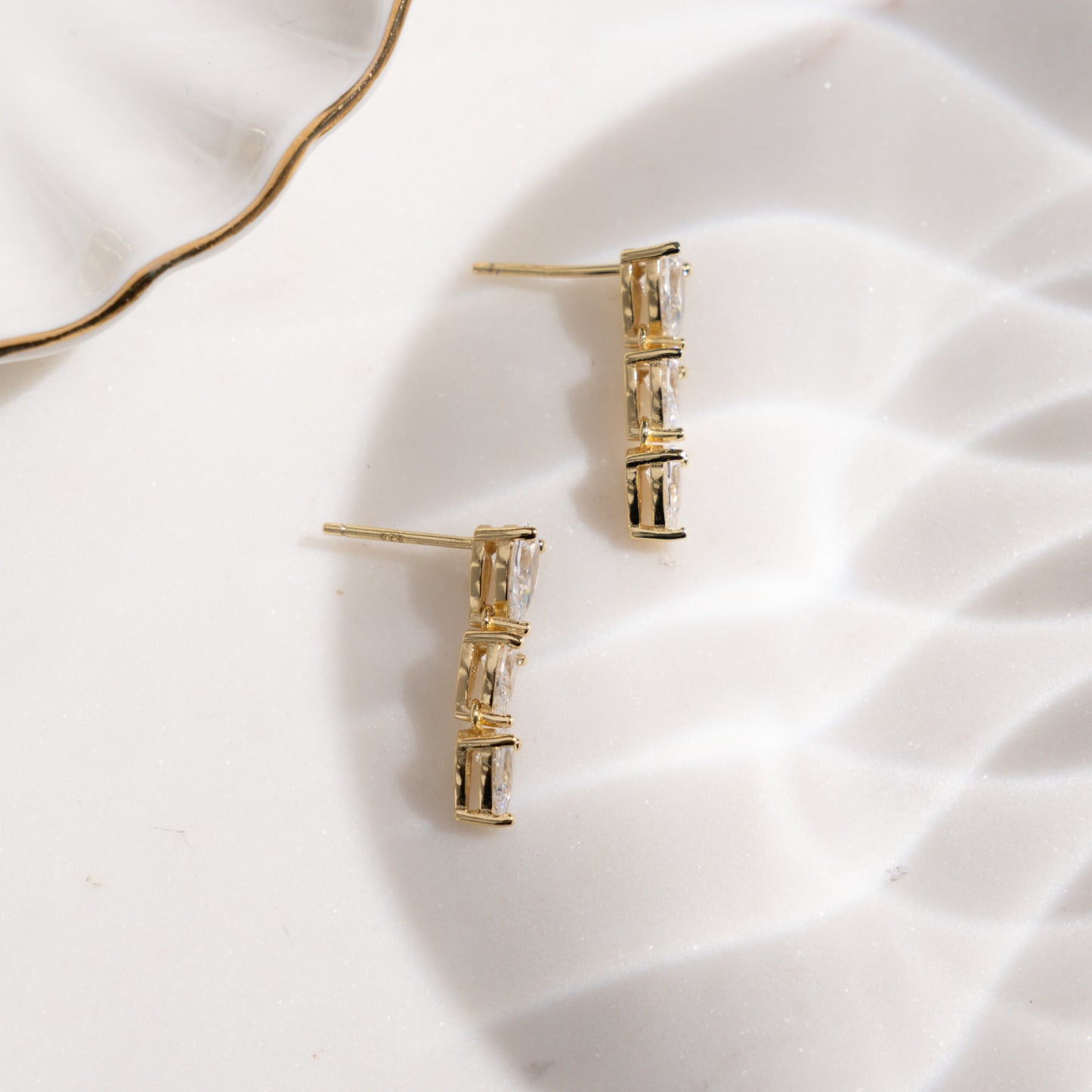flat lay of dainty earrings featuring teardrop gemstones.
