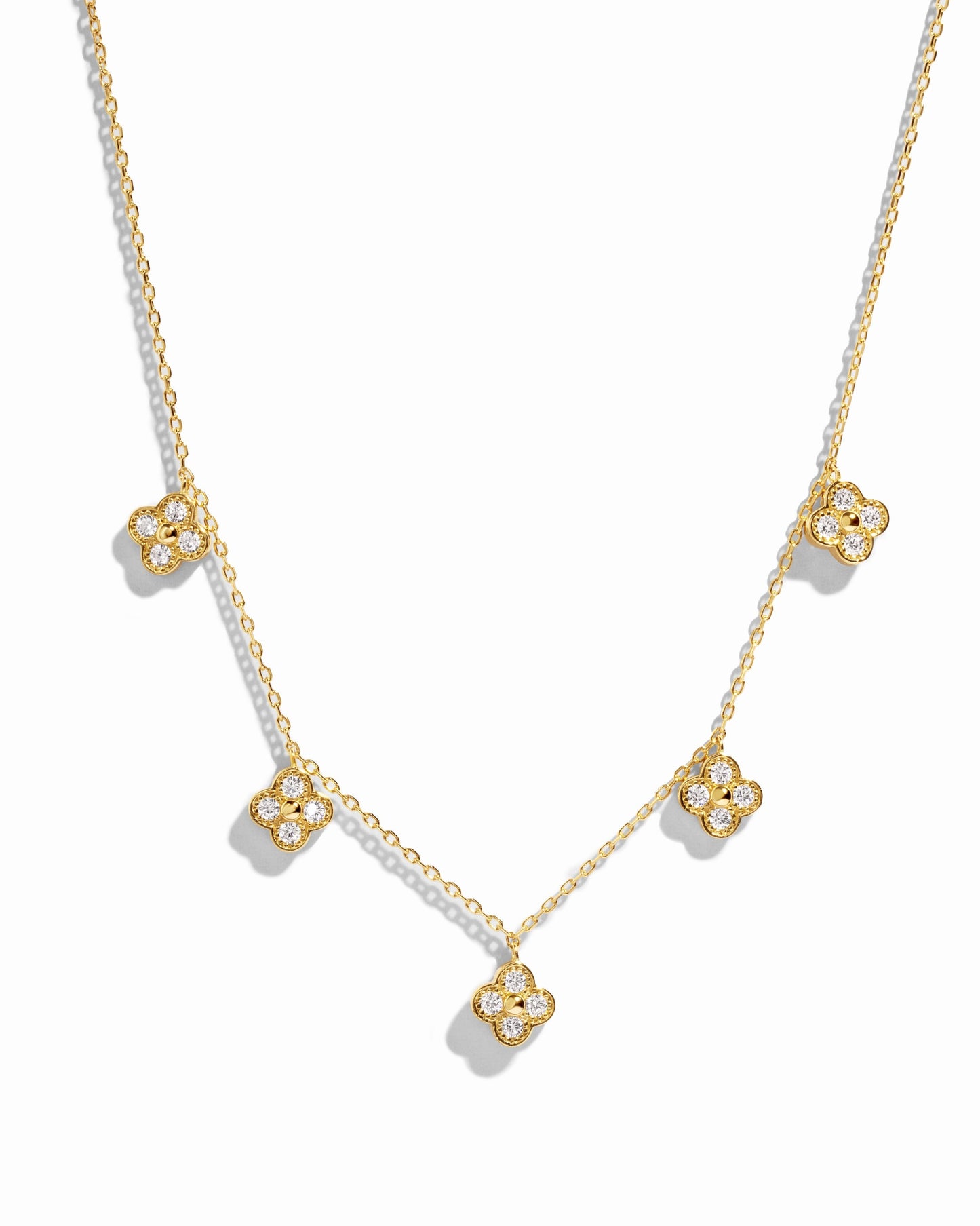 flat lay of a van cleef inspired charm necklace consisting of 5 small diamond four leaf clover charms