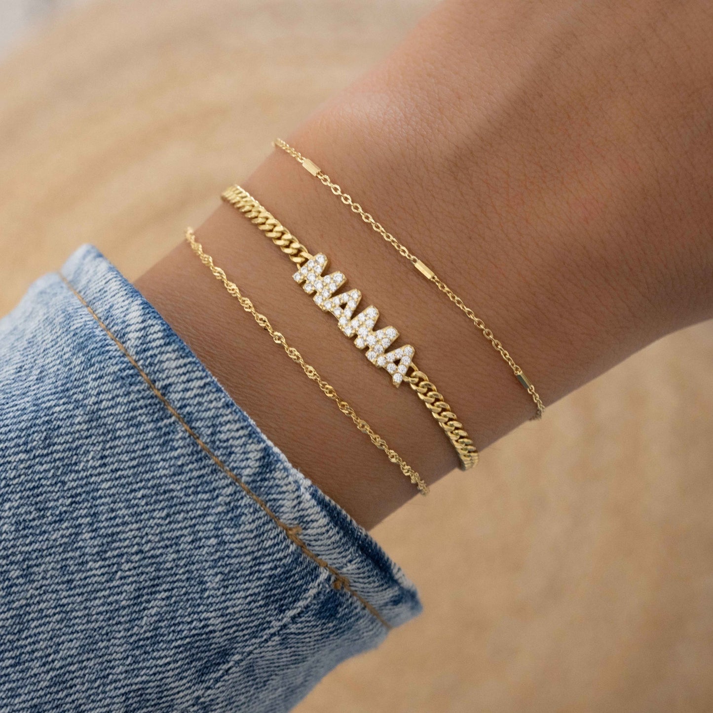 Model showcasing gold jewelry featuring charm bracelet with MAMA charm and gold chain
