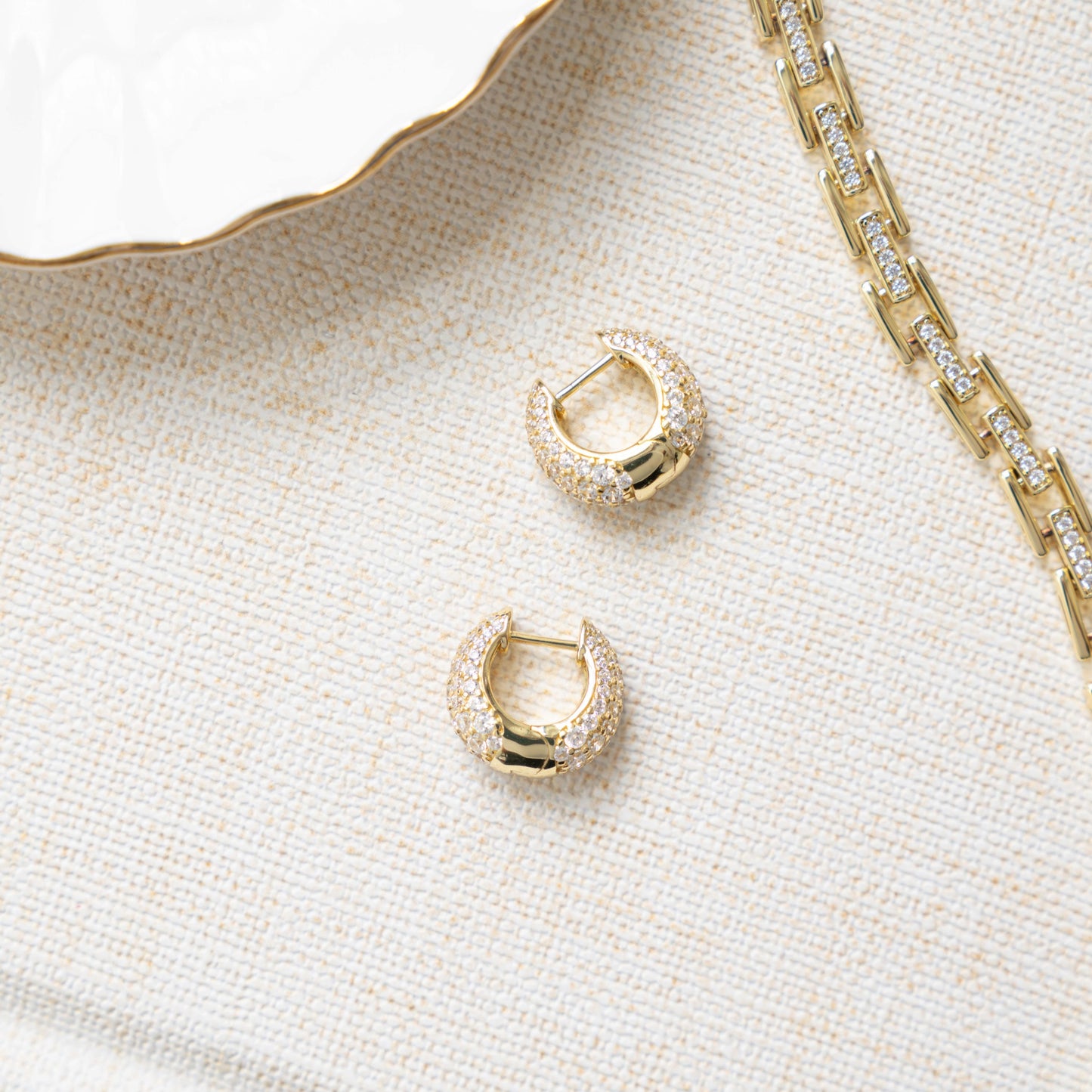 Closeup image of 14k gold plated earrings with gold huggie earring design