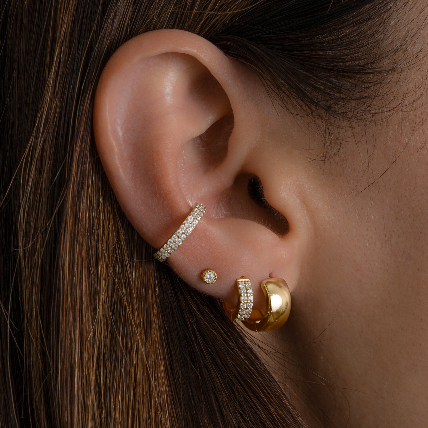 model wearing gold earrings featuring a cubic zirconia ear cuff