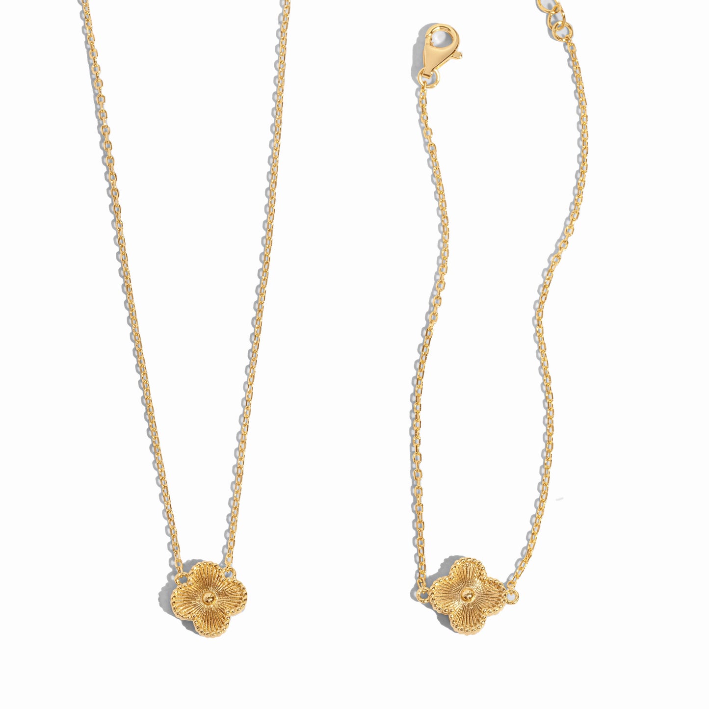 closeup image of gold four leaf clover pendant necklace and matching charm bracelet