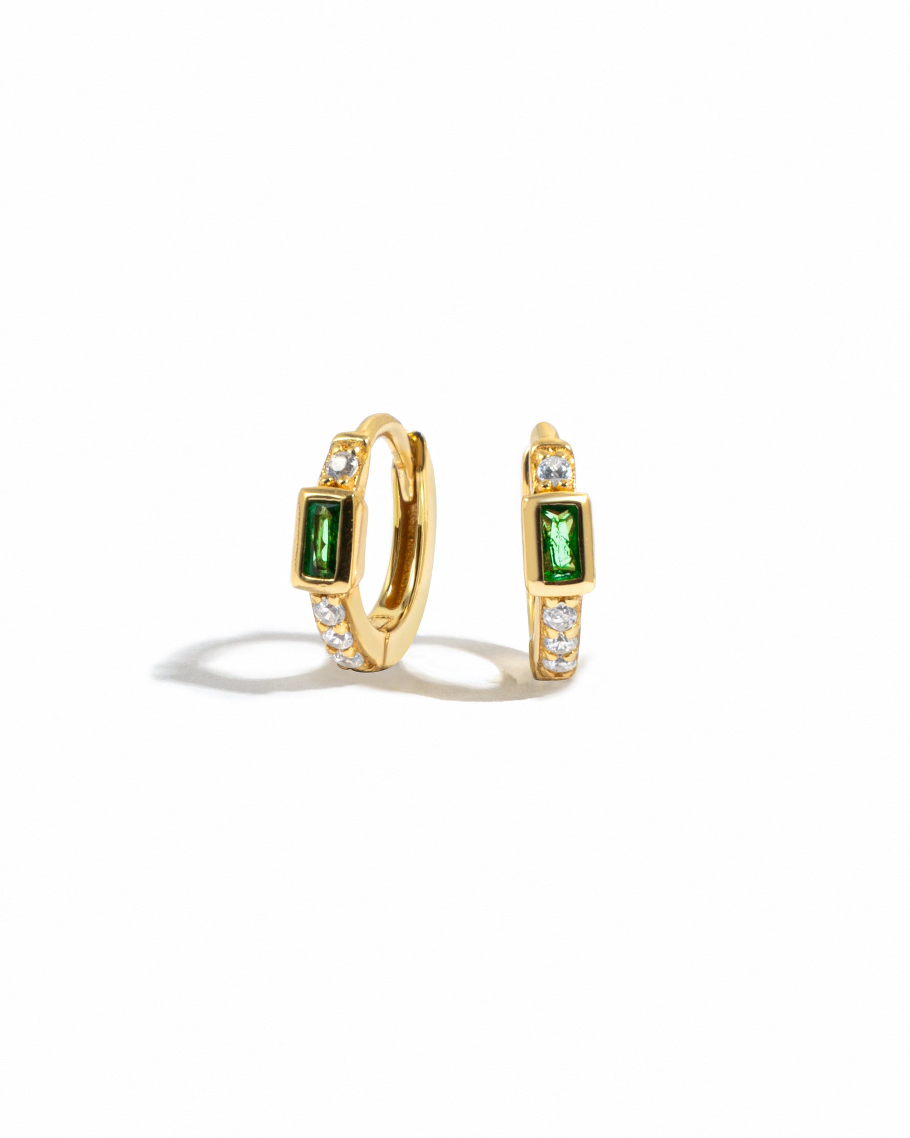 gold hoop earrings with cubic zirconia studded stones, and a emerald green baguette stone