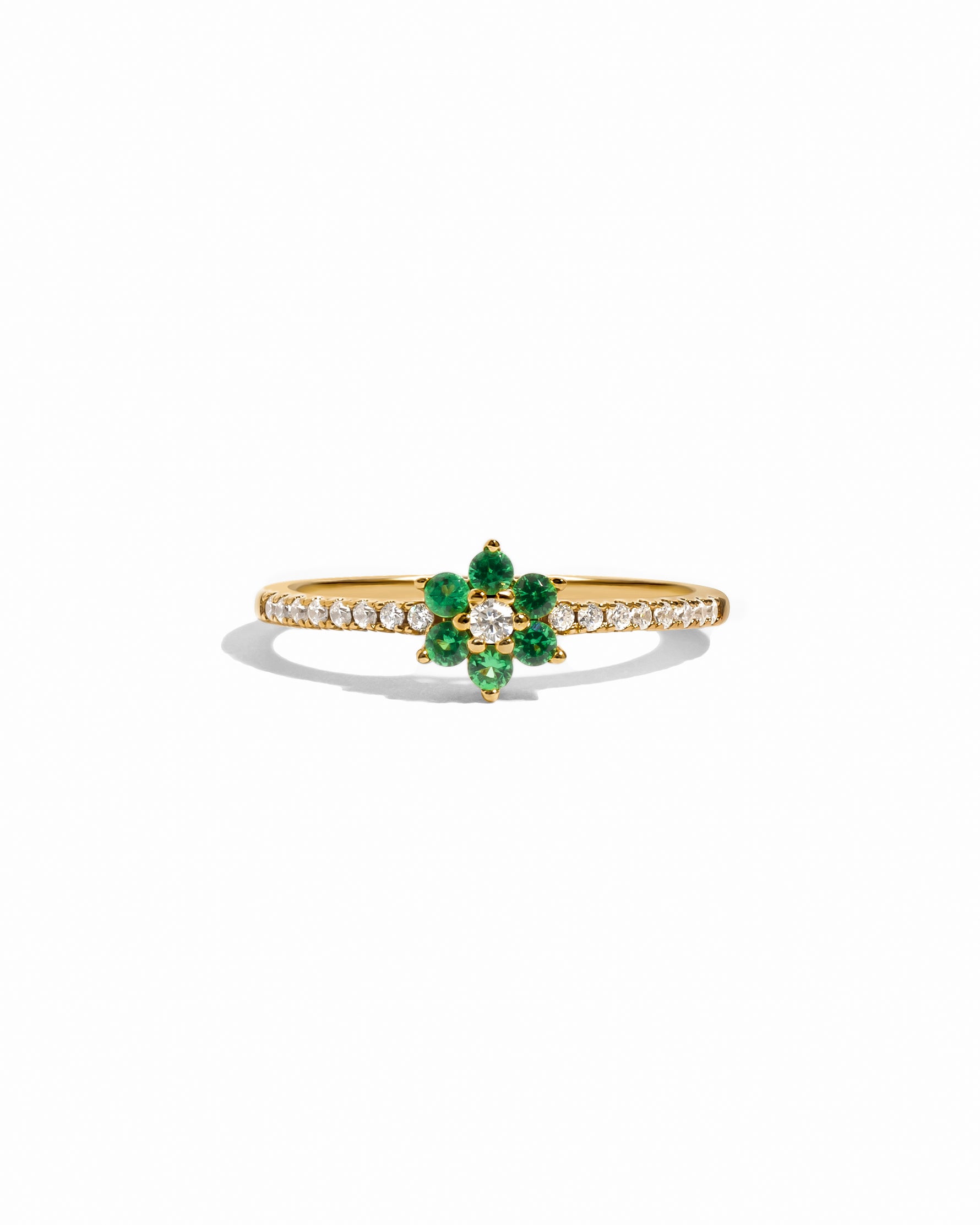 Gold ring with emerald green gemstone on a white background