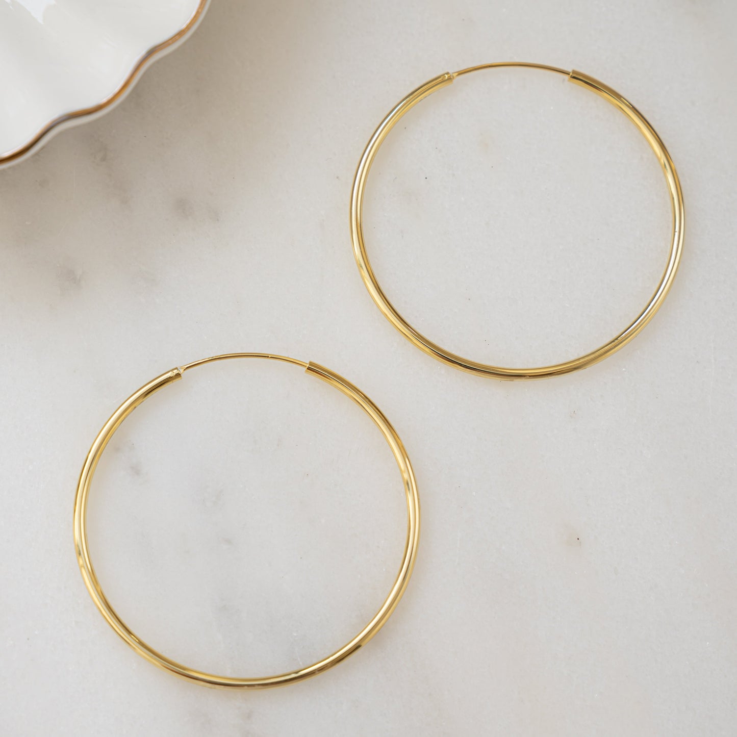 Closeup image of large hoop earring with threader earring closure style