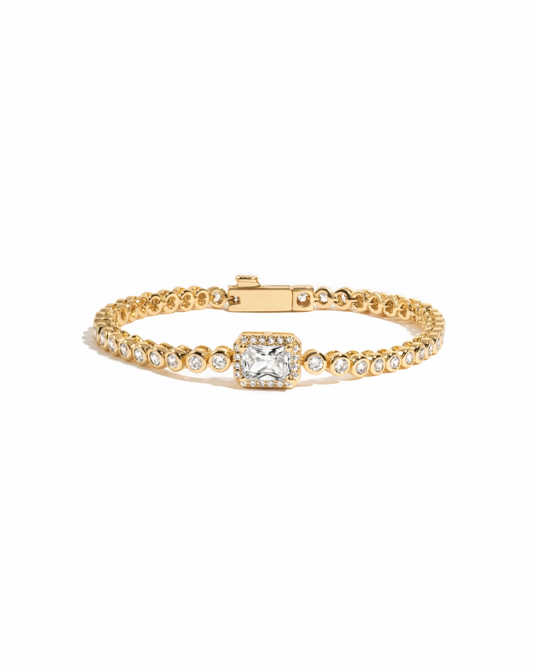 Gold tennis bracelet with a central baguette diamond on a white background