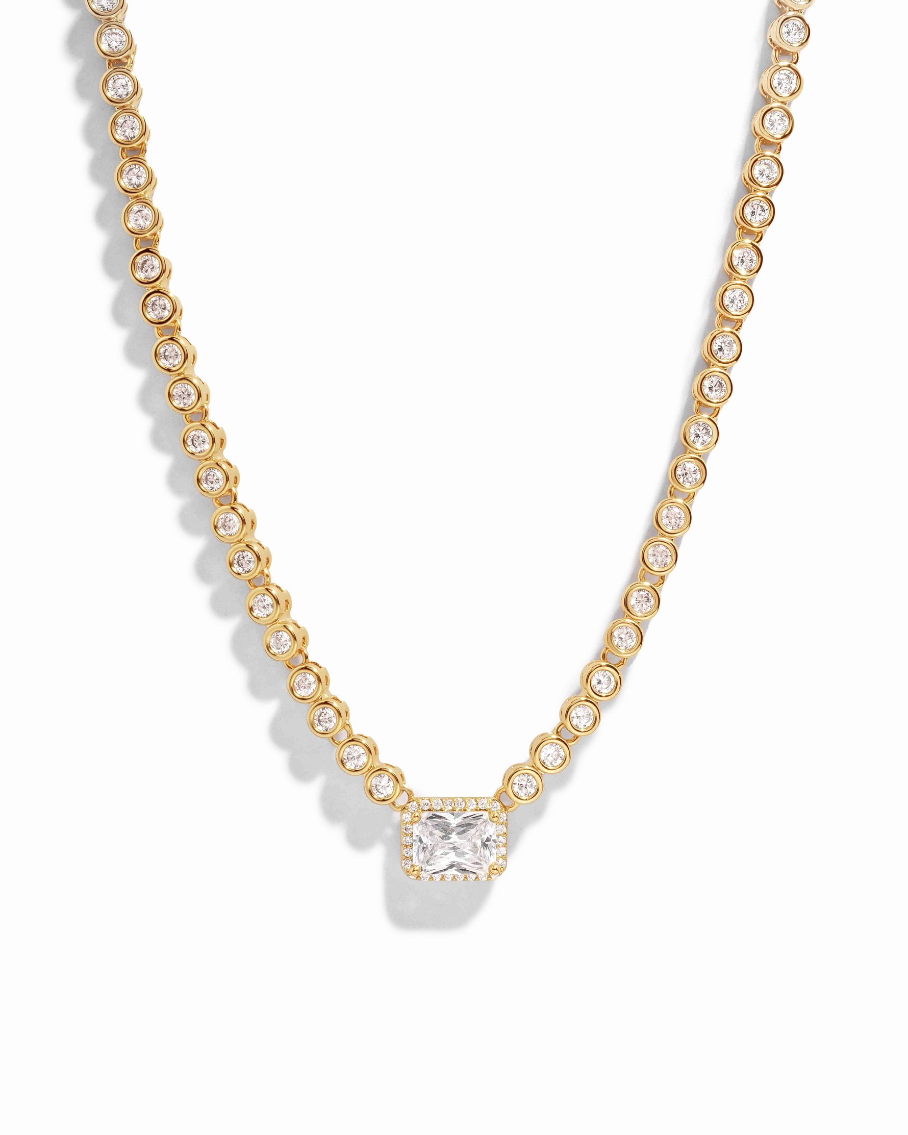Gold diamond baguette tennis necklace for women, with tiny round bezel settings on white background