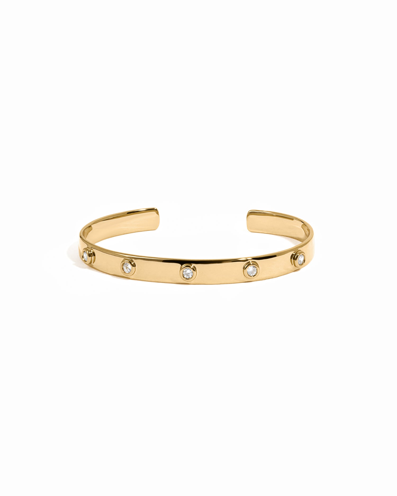 Gold cuff bracelet with small diamonds on a white background