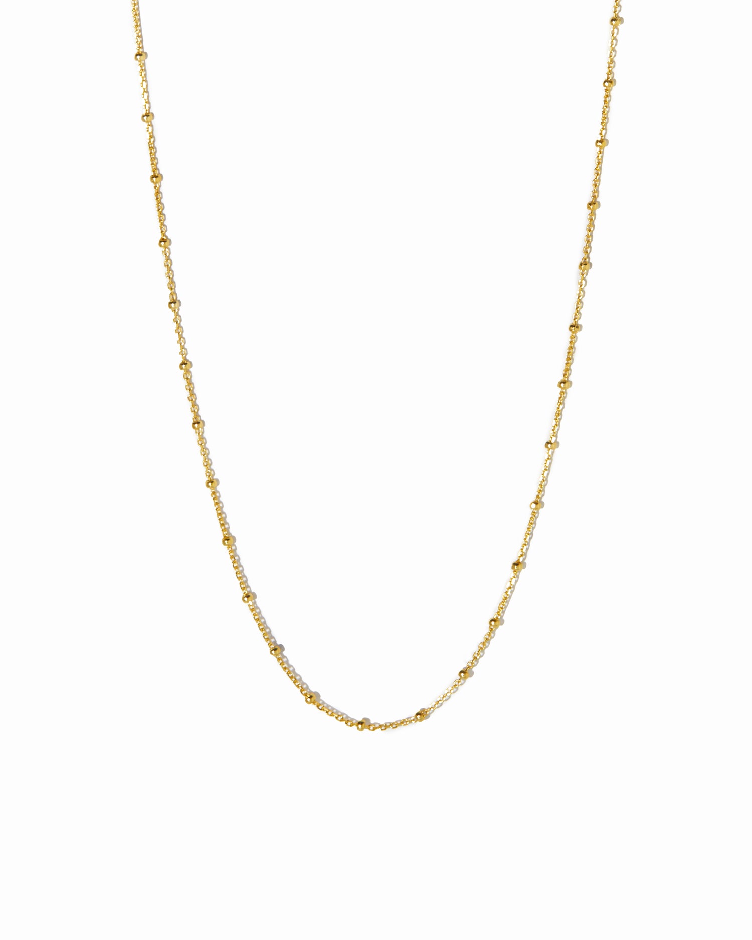 Close up image of gold simple beaded waist body chain on white background