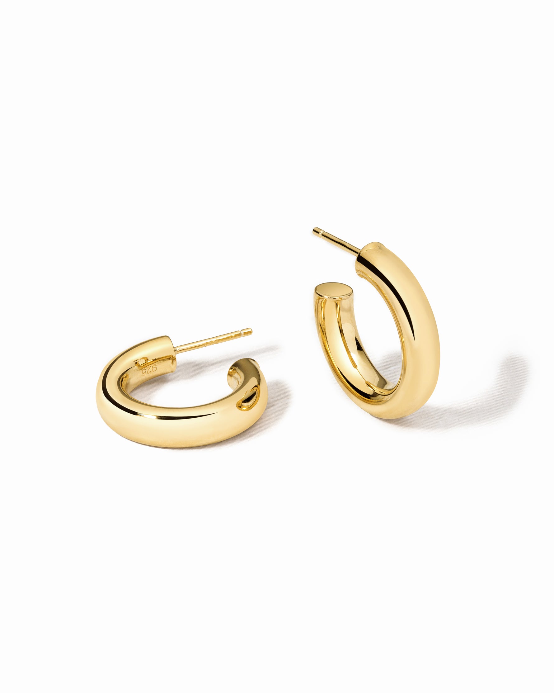 Gold chunky tube hoop earrings on a white background