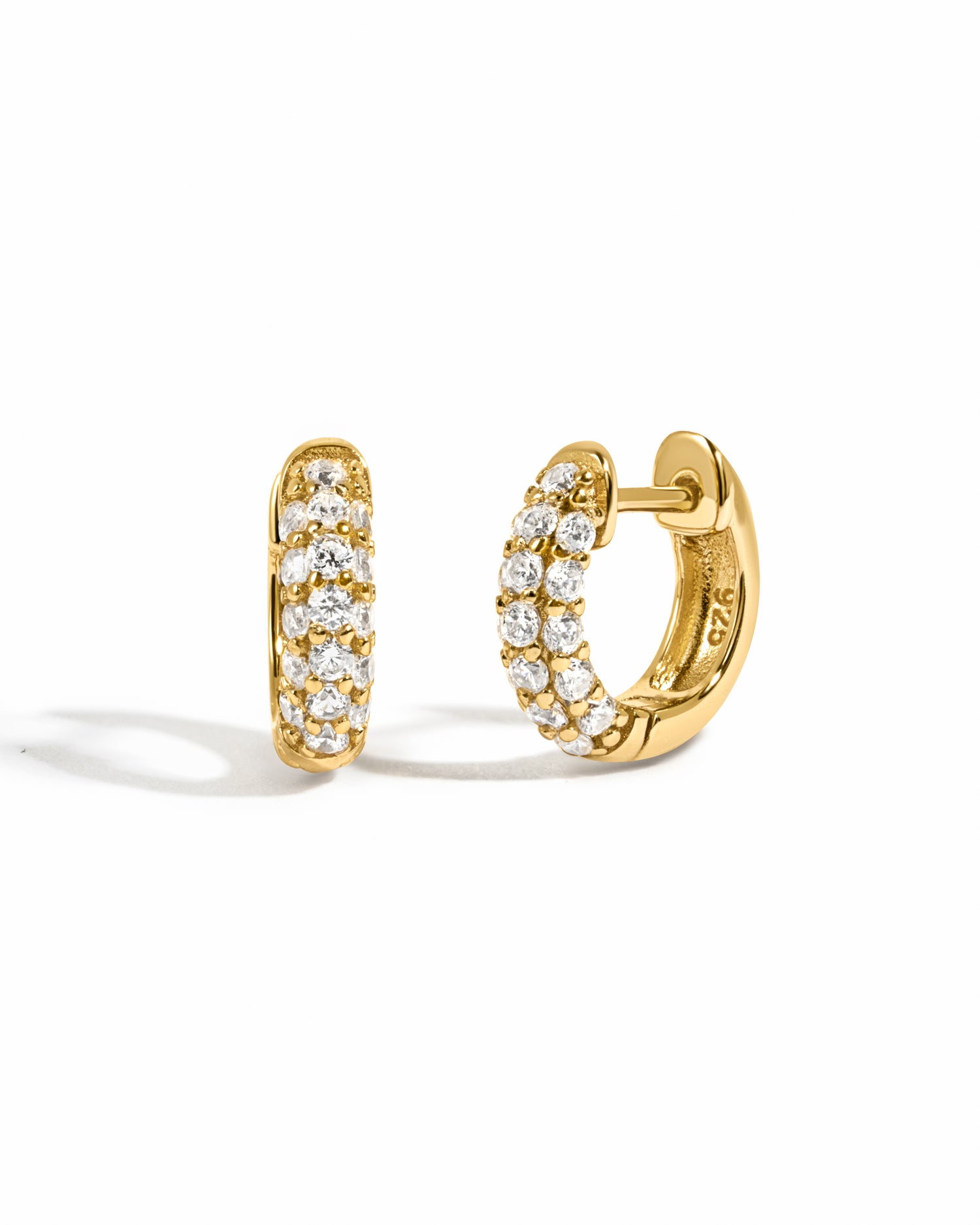 Gold hoop earrings with pave cubic zirconia stones on a white background