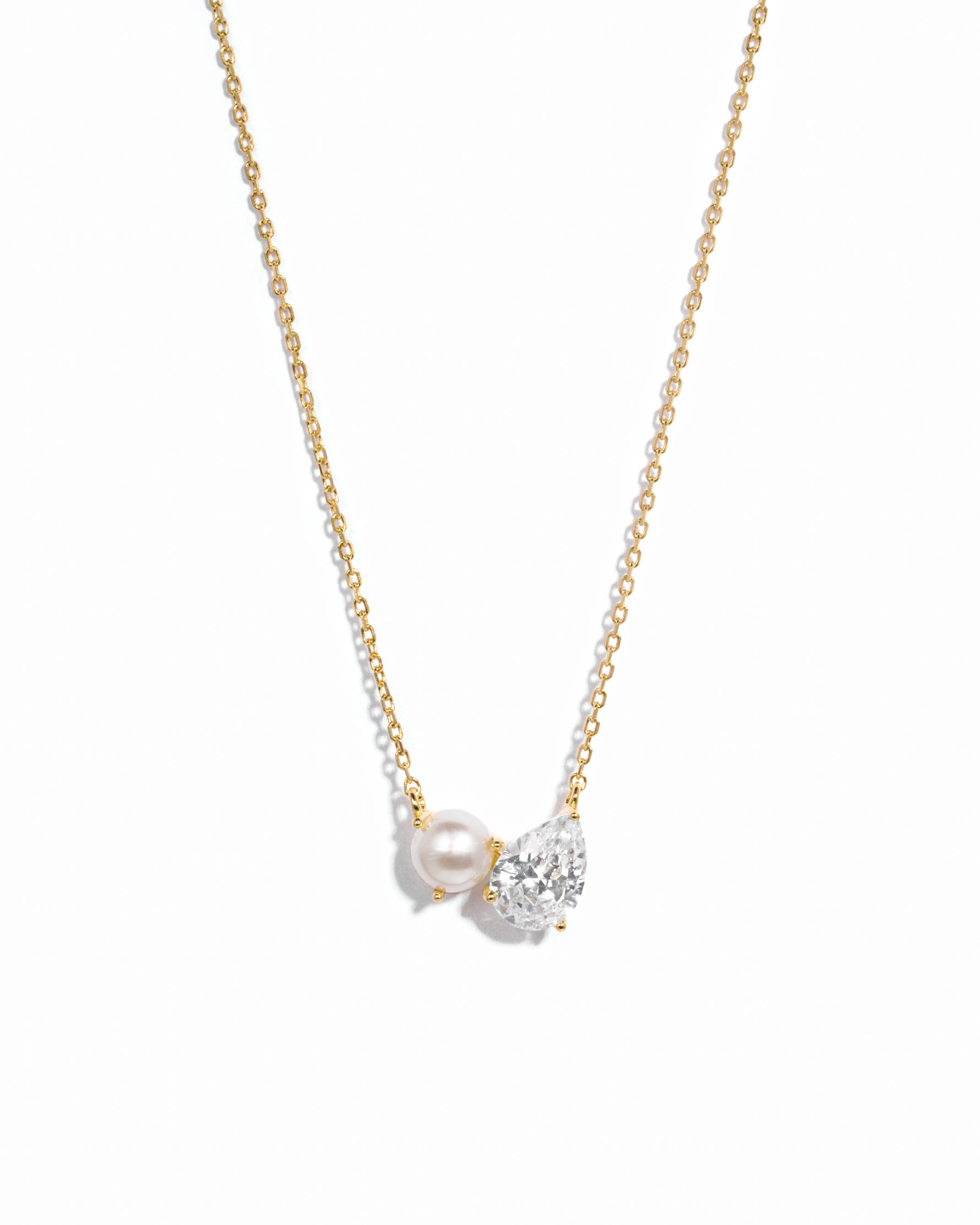 Necklace with a pearl and small diamond pendant on a gold chain against a white background