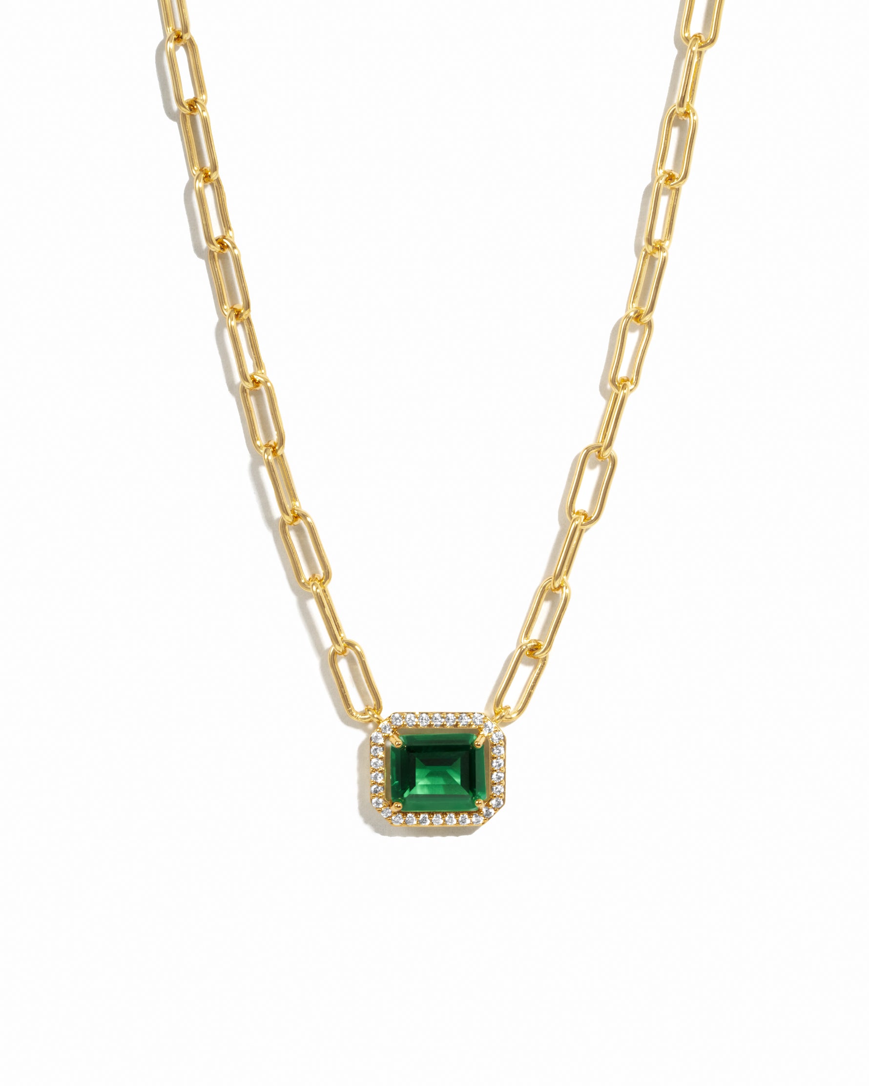 Gold necklace with a emerald green gemstone pendant on a white background