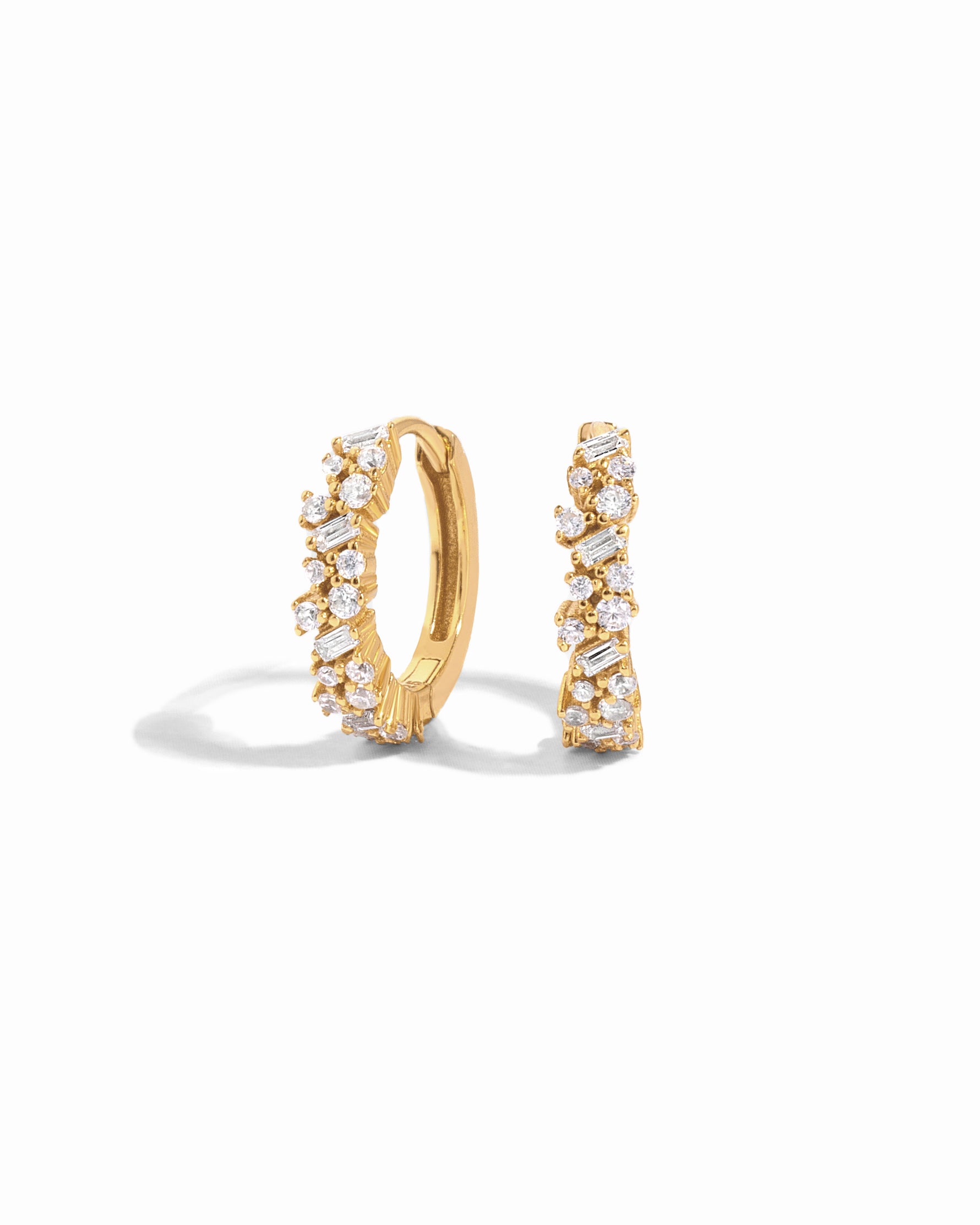 Gold huggie hoop earrings with diamonds on a white background