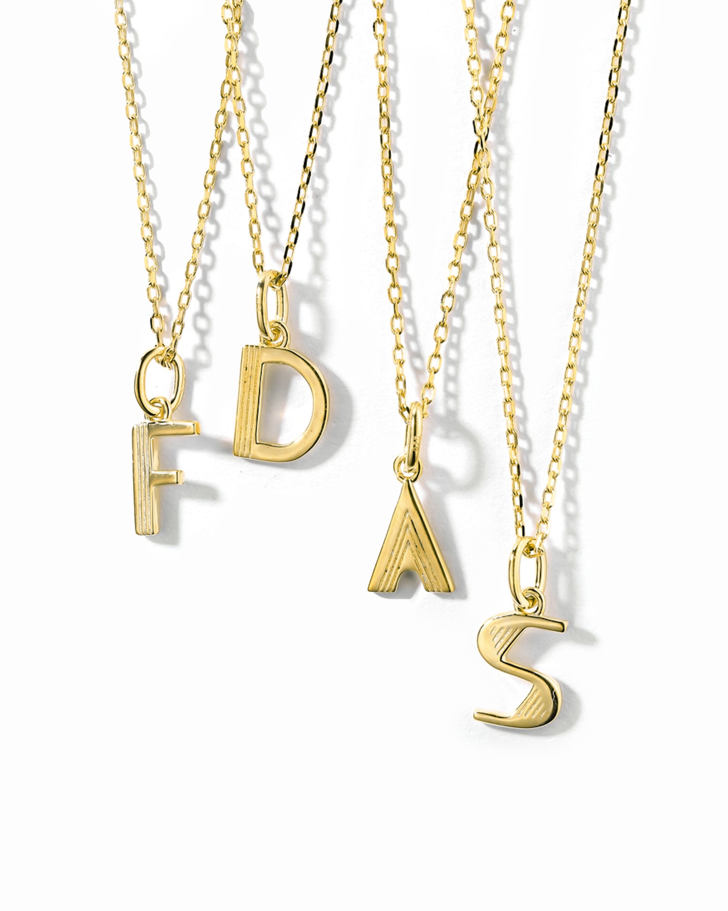 gold personalized jewelry, featuring different initial necklaces on a white background