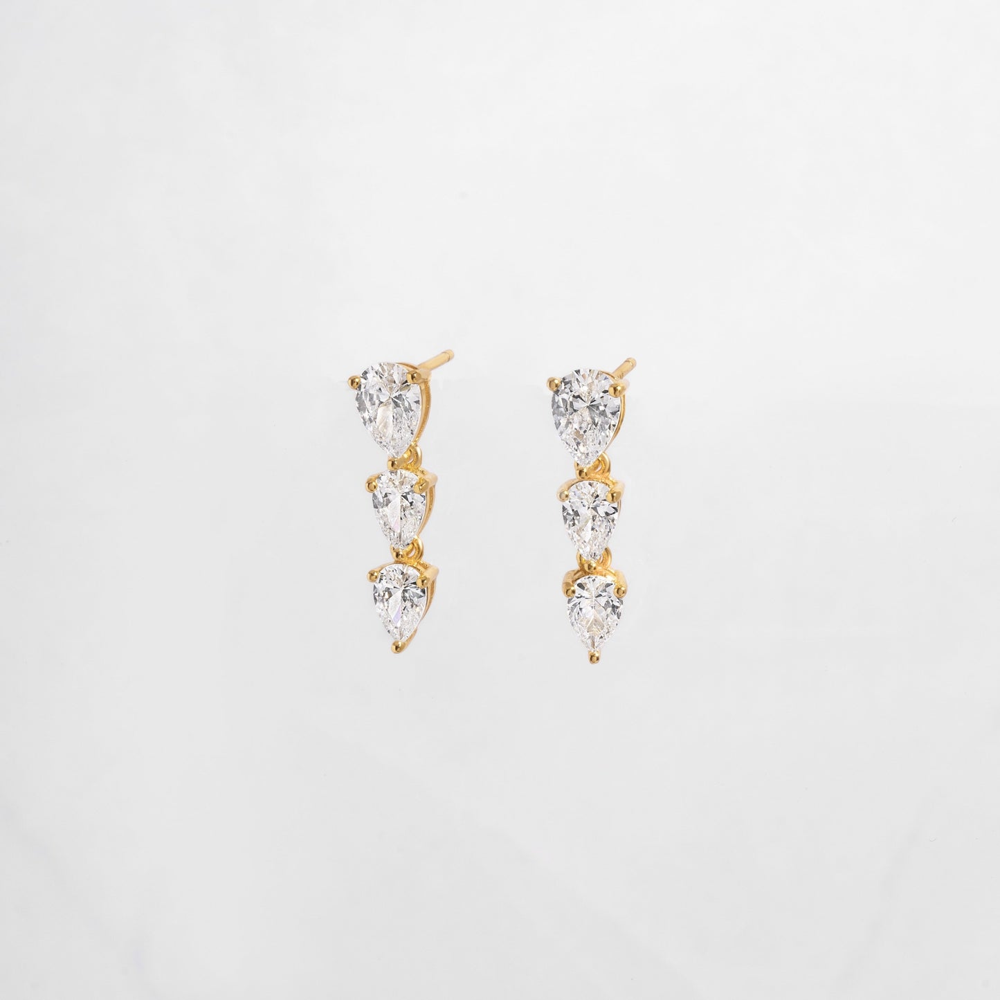 close up of cubic zirconia gemstone earrings with a pear drop shape set in gold.