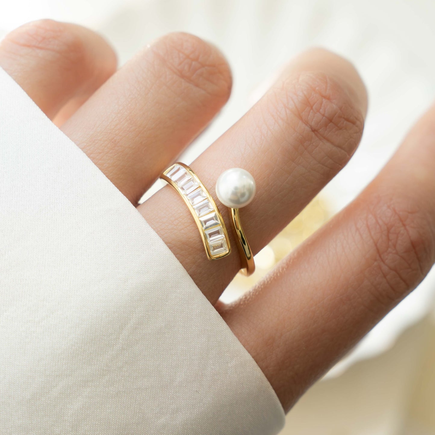 Model wearing freshwater pearl baguette ring with unique spiral ring design in gold