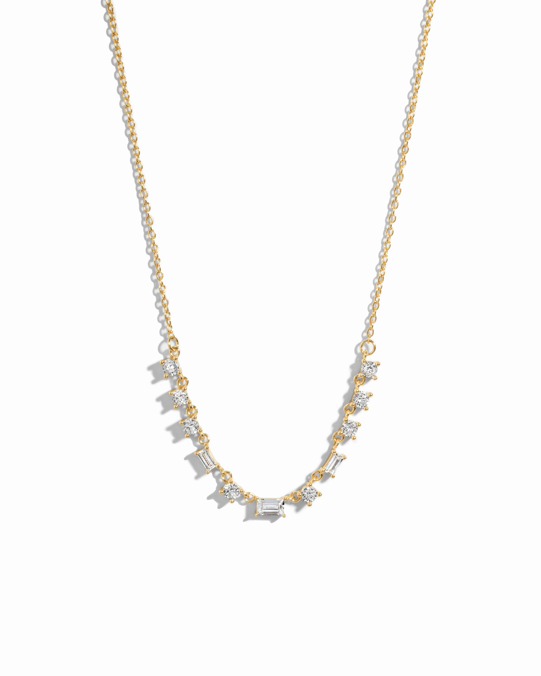 Closeup image of gold diamond baguette necklace on white background