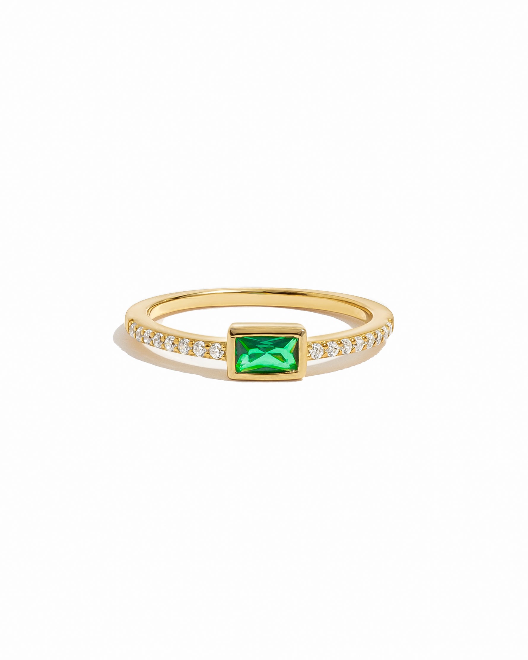 Gold ring with a green gemstone and small diamonds on a white background