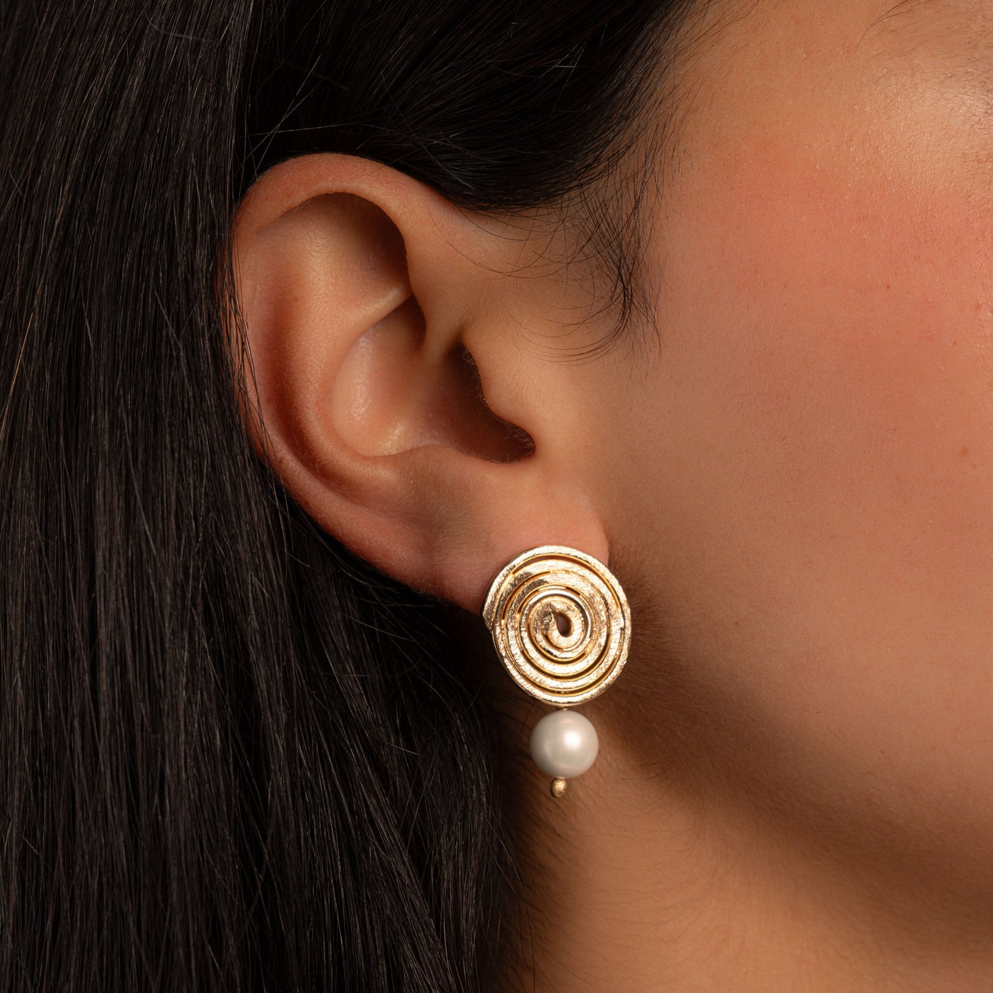 model wearing gold spiral statement earrings