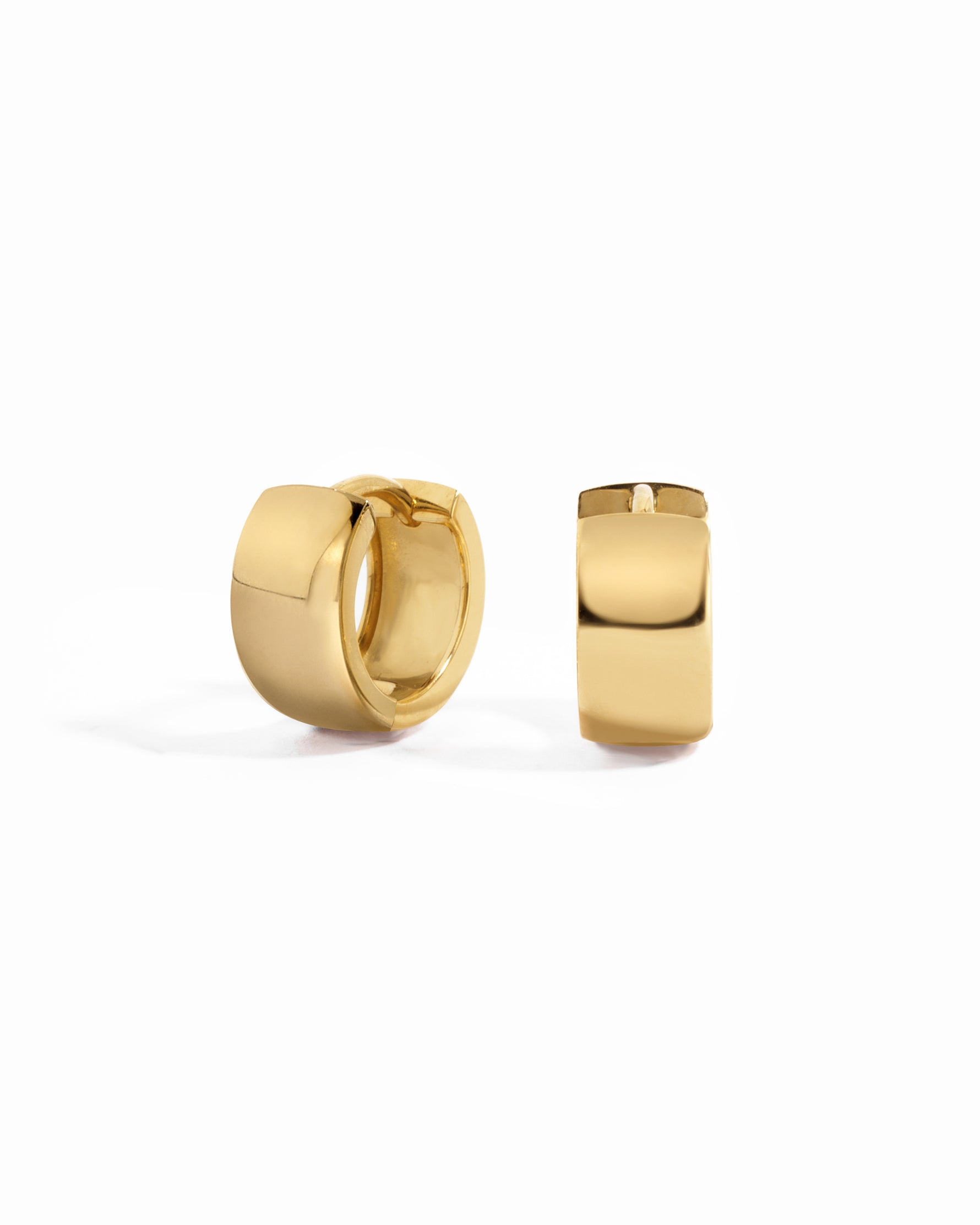 Gold chunky huggie hoop earrings on a white background