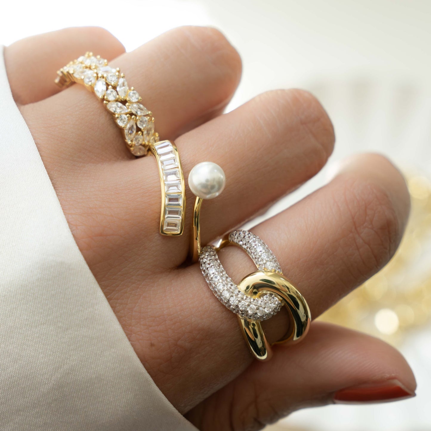Model wearing statement rings, featuring a criss cross ring design with sterling silver and 14k gold