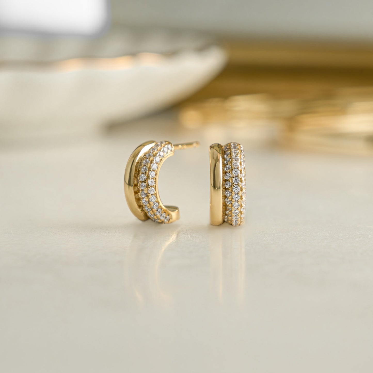 closeup image of dainty earrings featuring cubic zirconia stones wrapped on huggie earrings