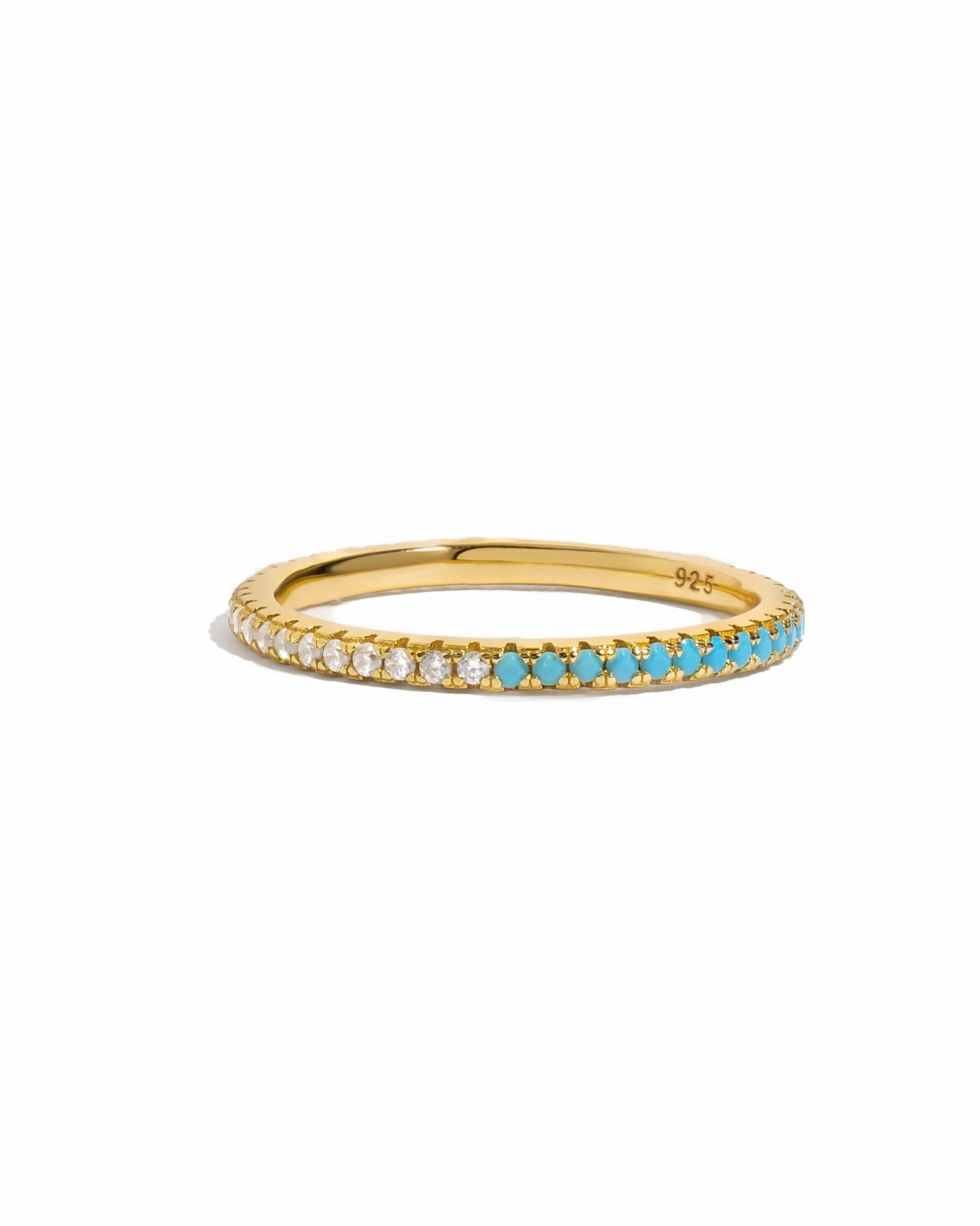 Gold ring with half white cubic zirconia half turquoise stones on a white background