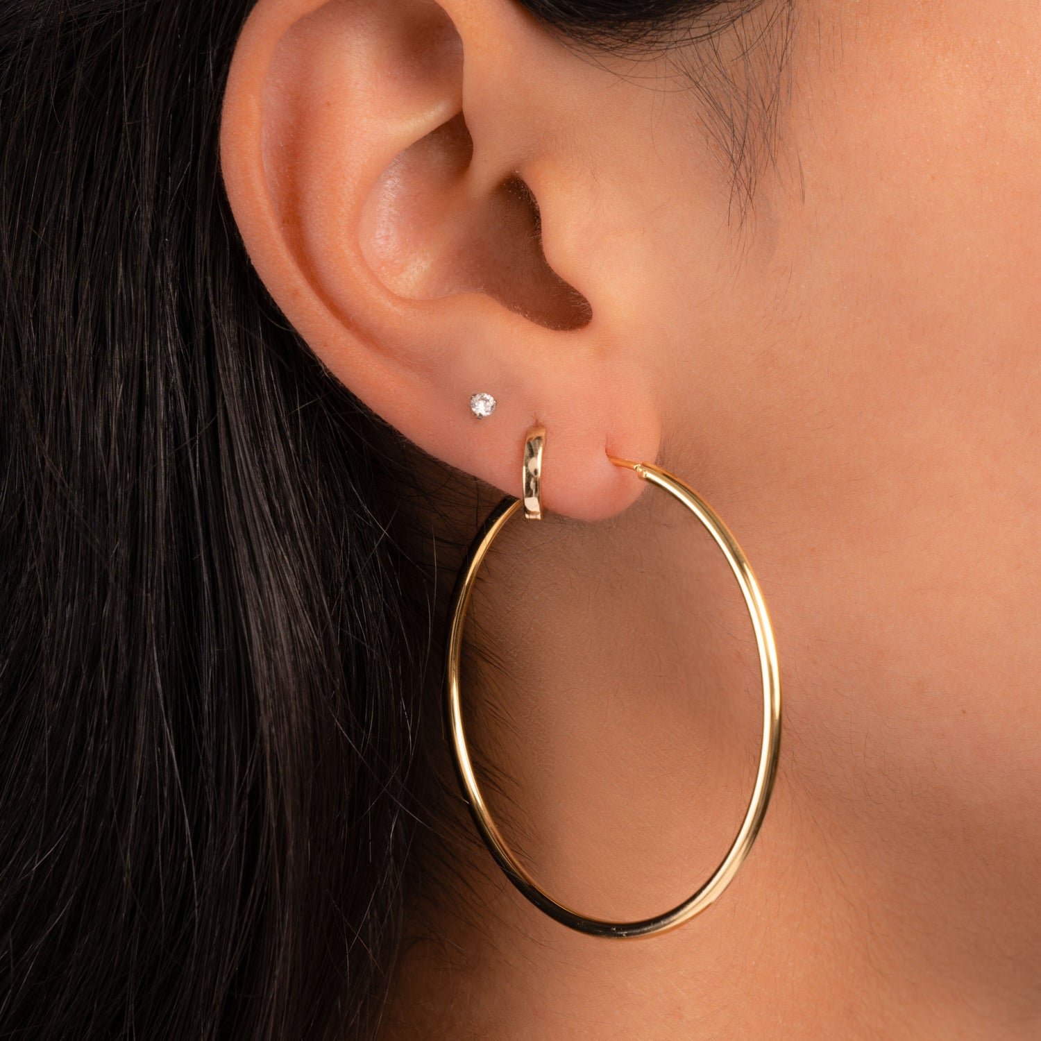Model wearing gold jewelry featuring large hoop earring