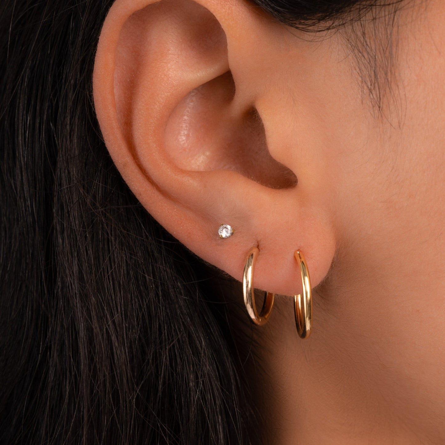 Model wearing gold jewelry featuring gold dainty hoop earrings